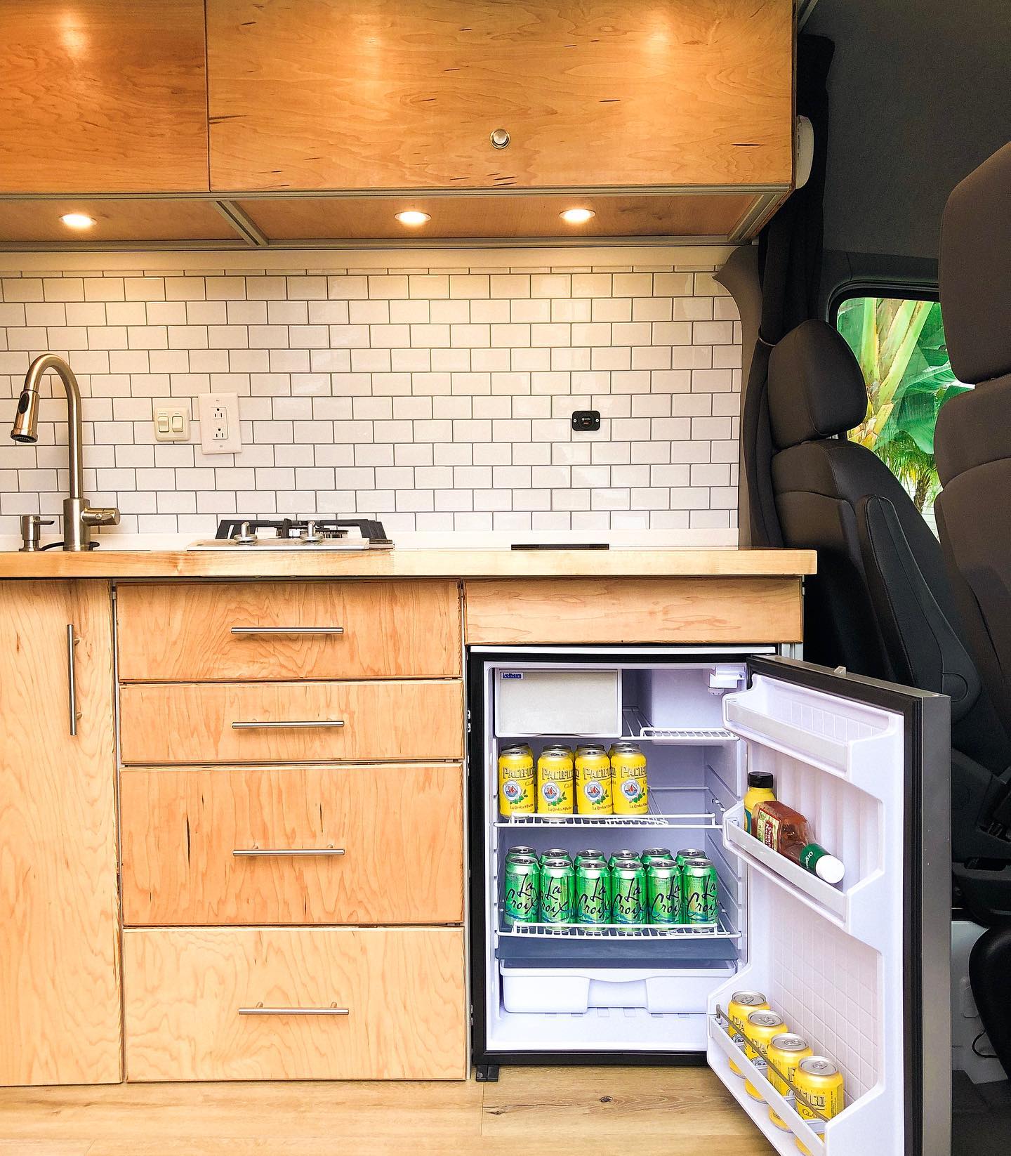 a kitchen with a small refrigerator filled with cans of soda