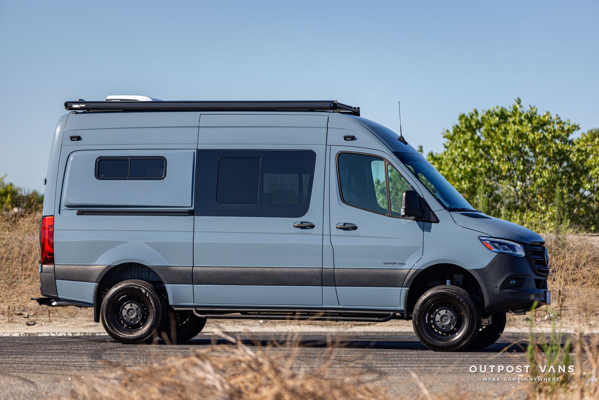 A gray van is parked on the side of the road in a field.