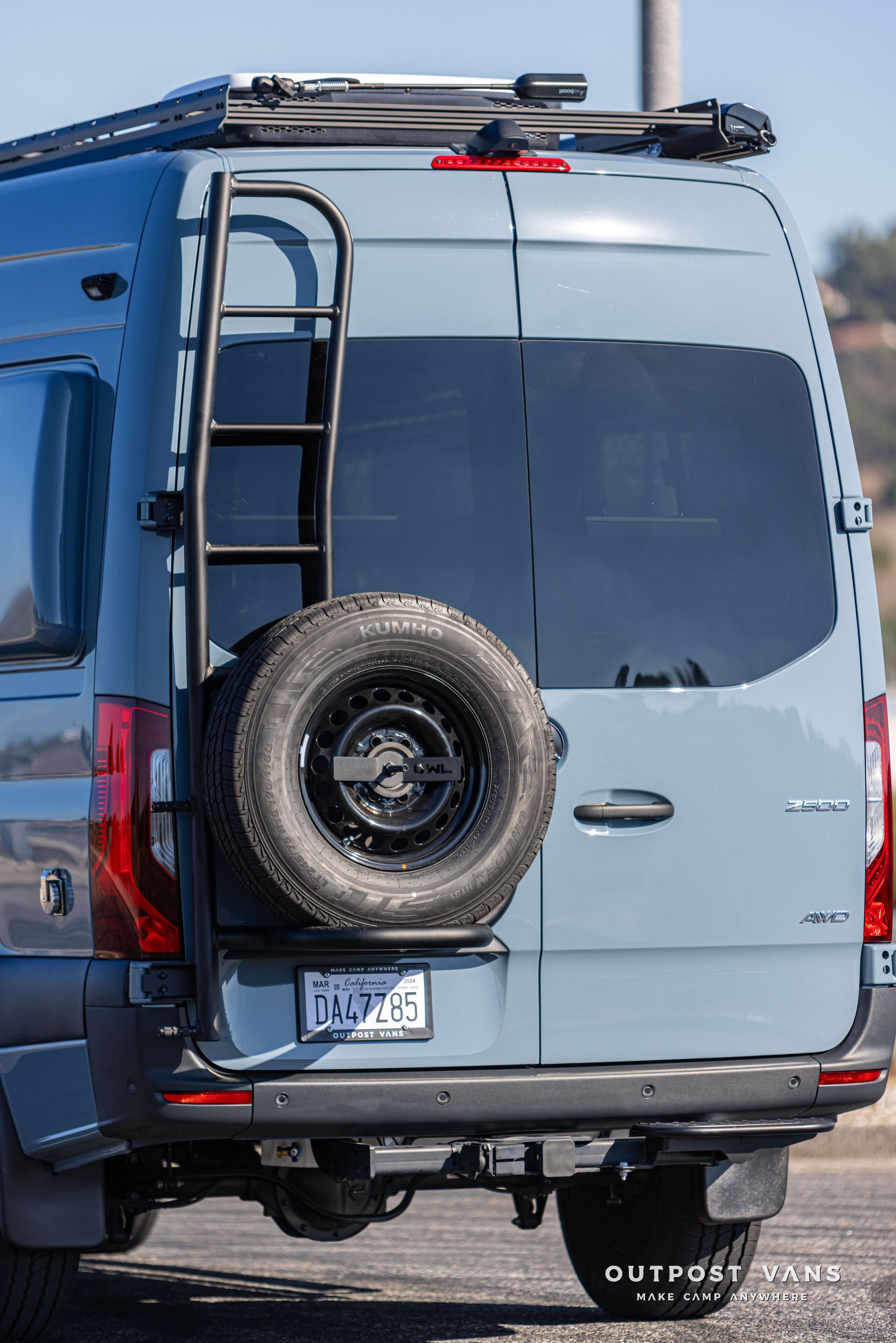 A blue van with a ladder attached to the back of it.