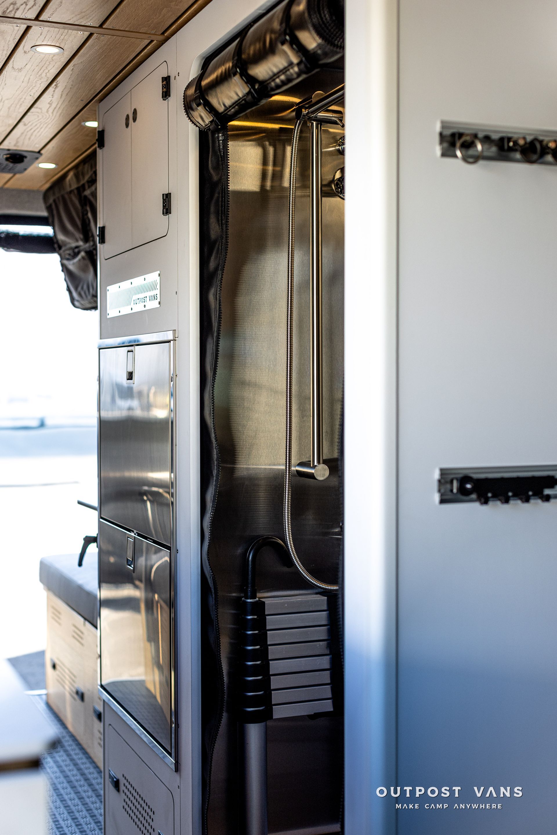 A kitchen in a van with stainless steel appliances and a sink.
