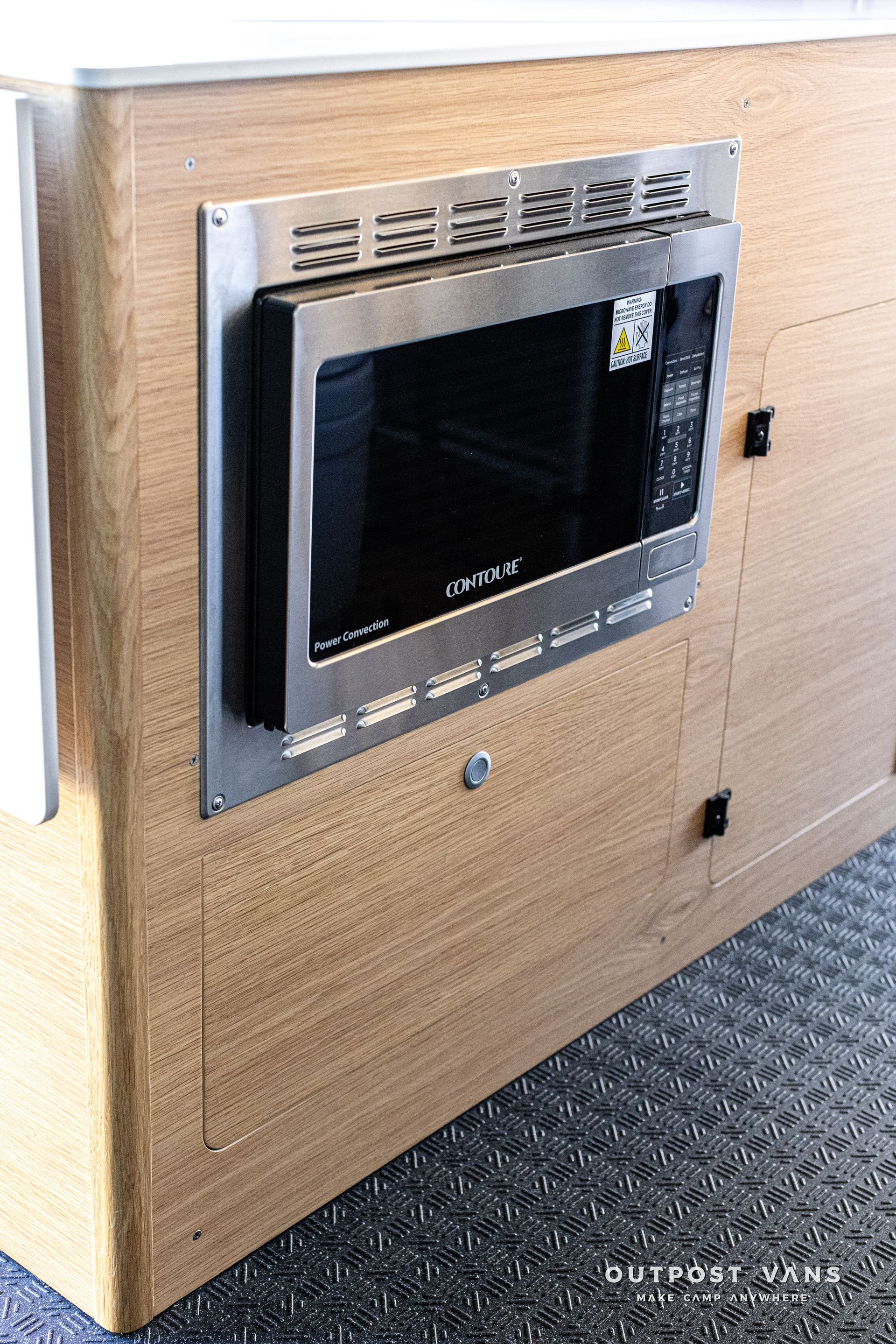 A microwave oven is mounted to the side of a wooden cabinet.