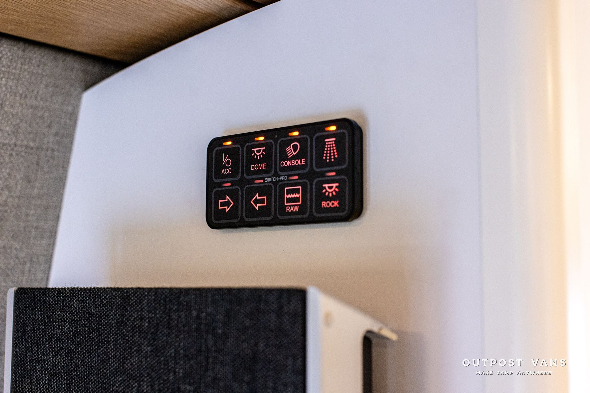 A close up of a remote control on a wall next to a speaker.