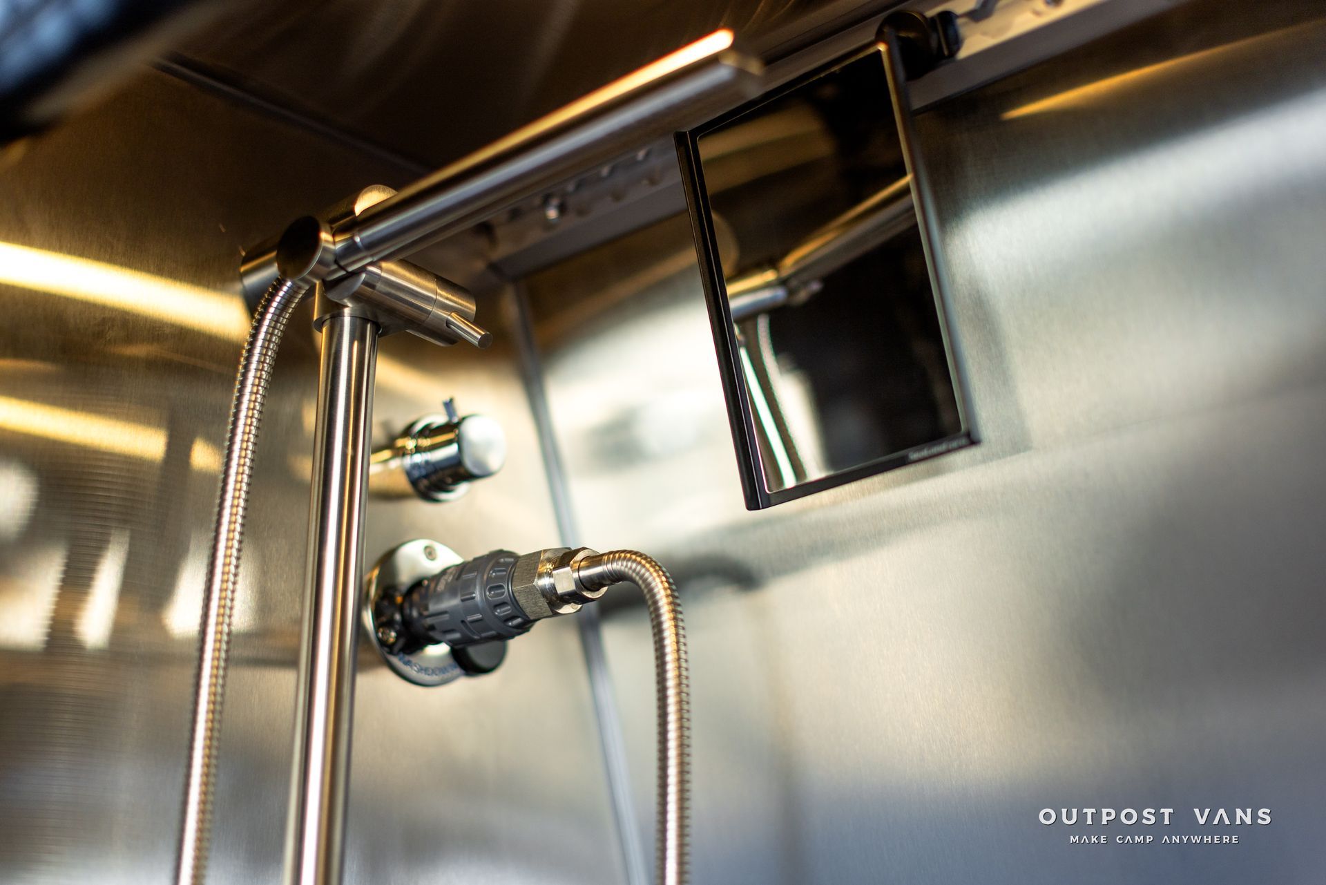 A stainless steel wall with a faucet and a mirror