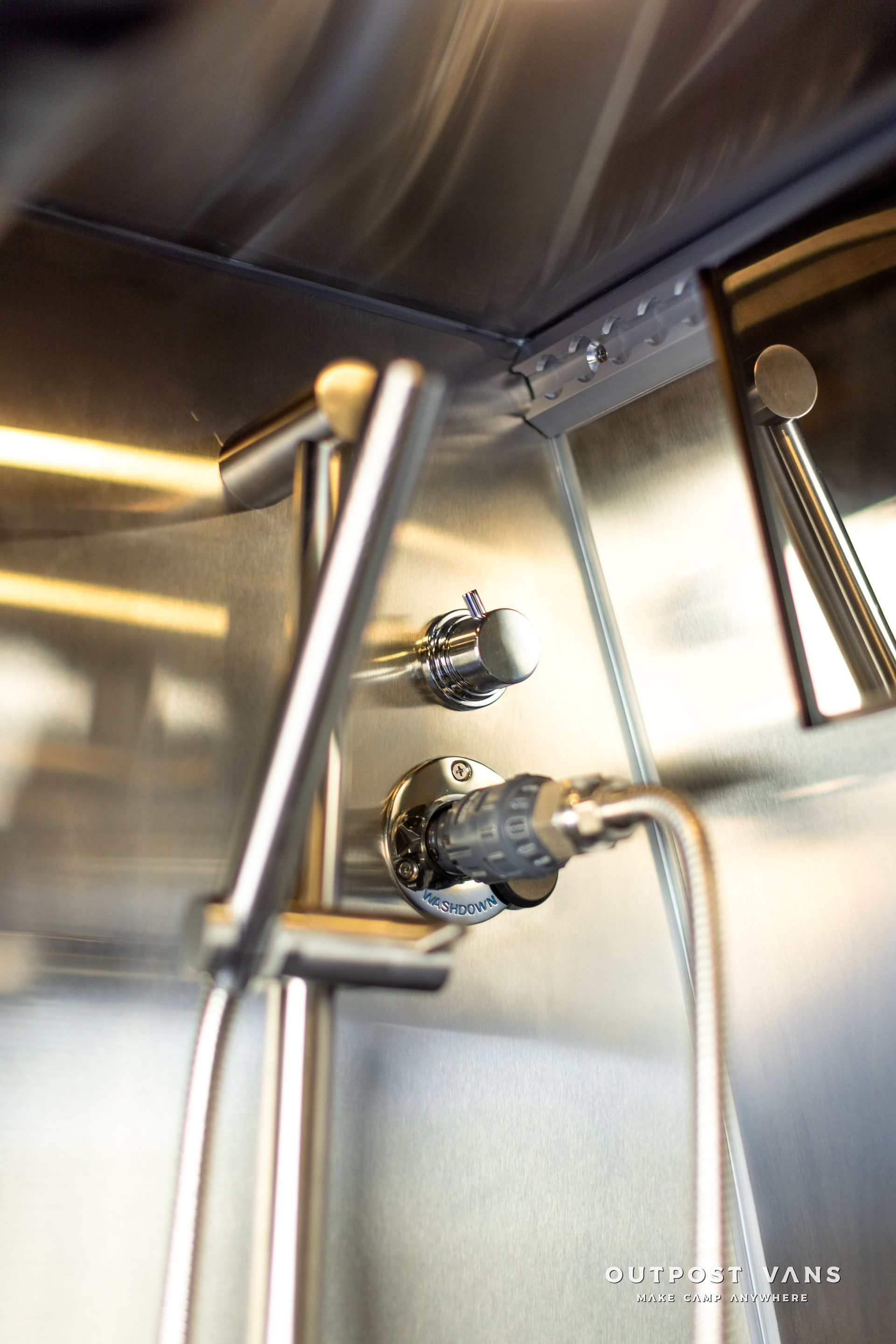 A stainless steel shower head is attached to a stainless steel wall.