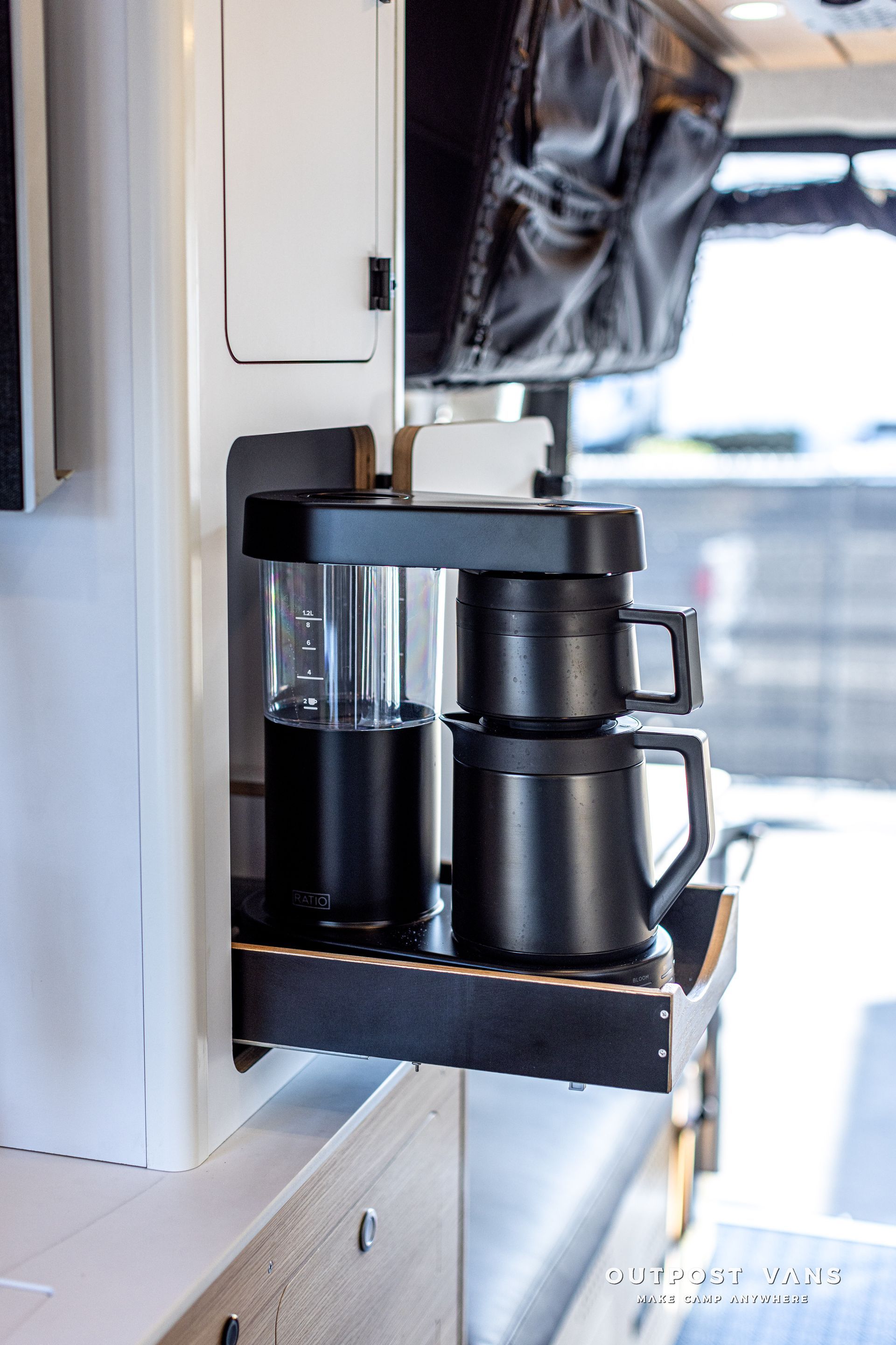 A coffee maker is sitting on a shelf in a kitchen.