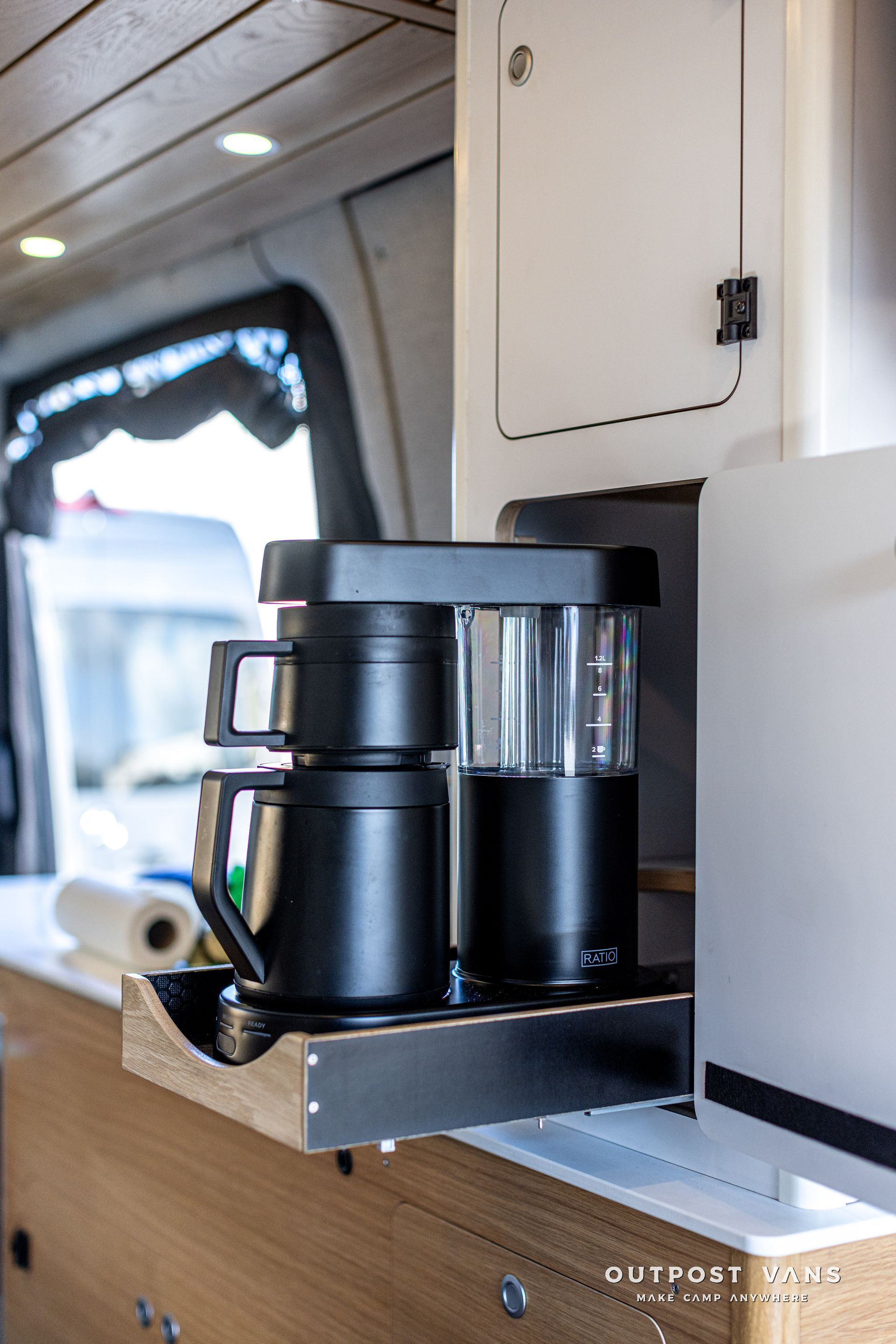 A coffee maker is sitting on a shelf in a van.