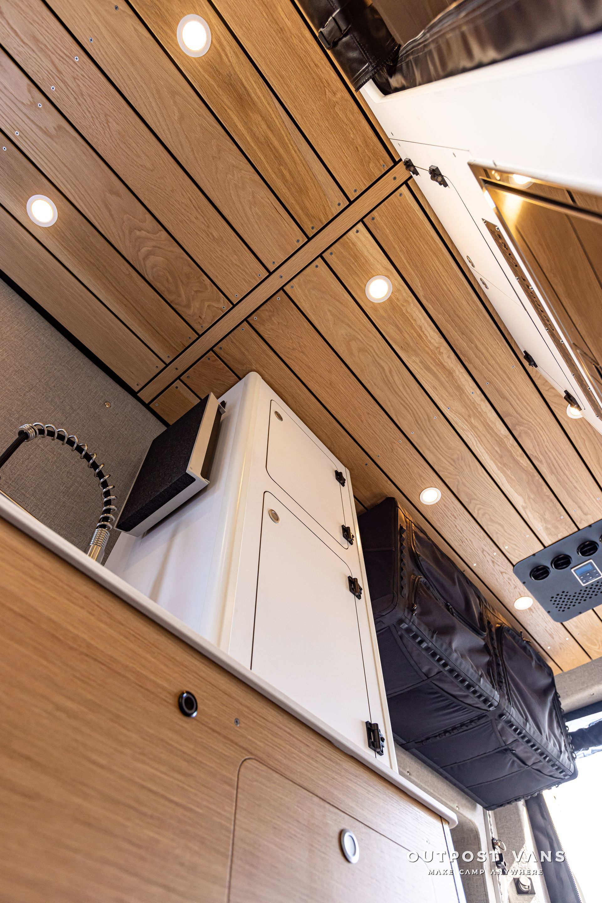 A kitchen in a van with a wooden ceiling and a sink.
