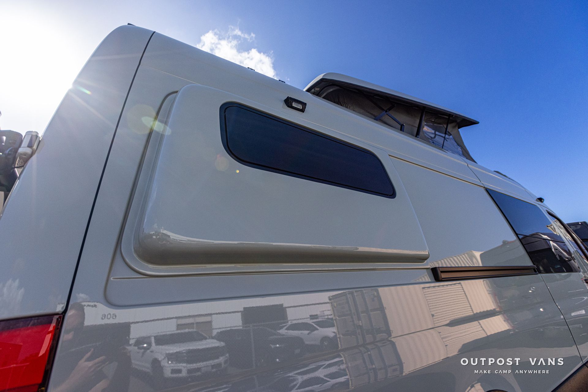 A van with a window on the side of it is parked in a parking lot.