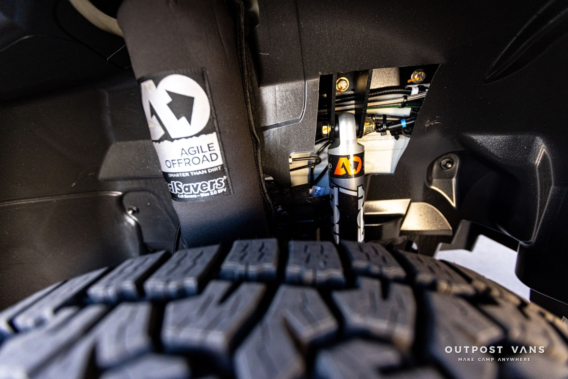 A close up of a tire and shock absorber on a truck.