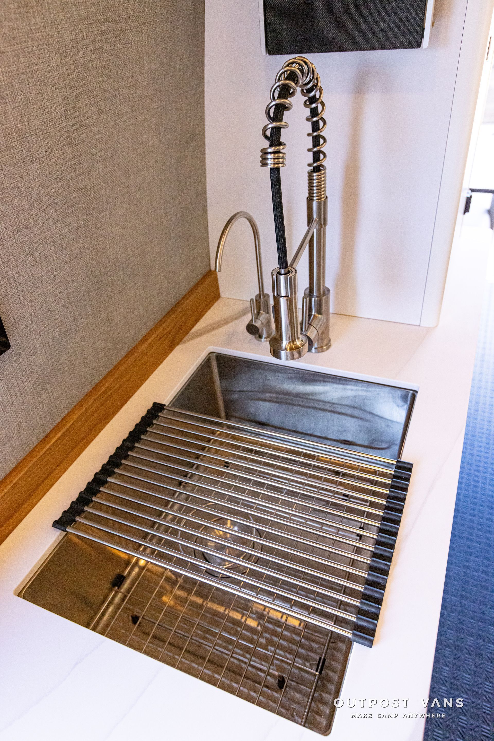 A kitchen sink with a faucet and a drying rack