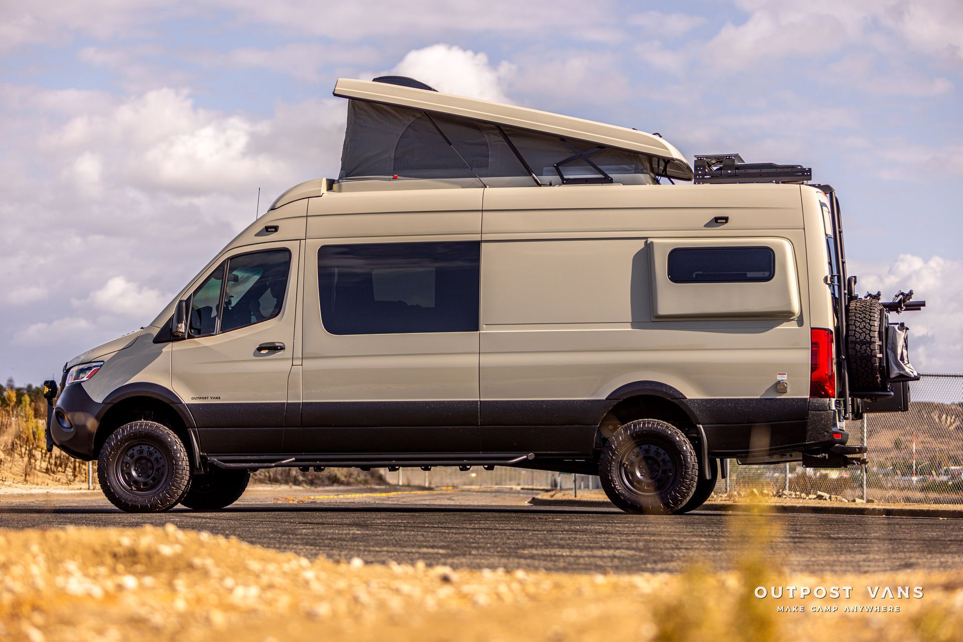 A van with a pop up roof is parked on the side of the road.
