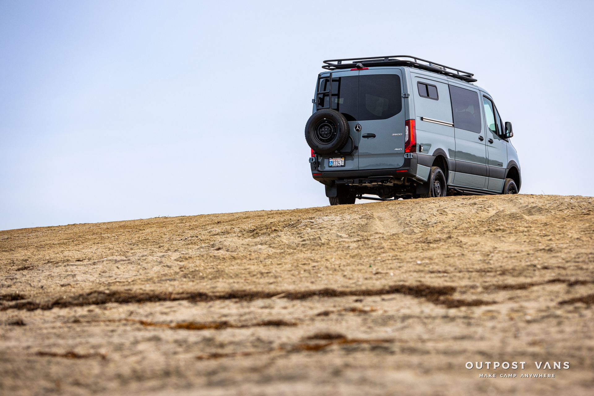 A van is parked on top of a sandy hill.