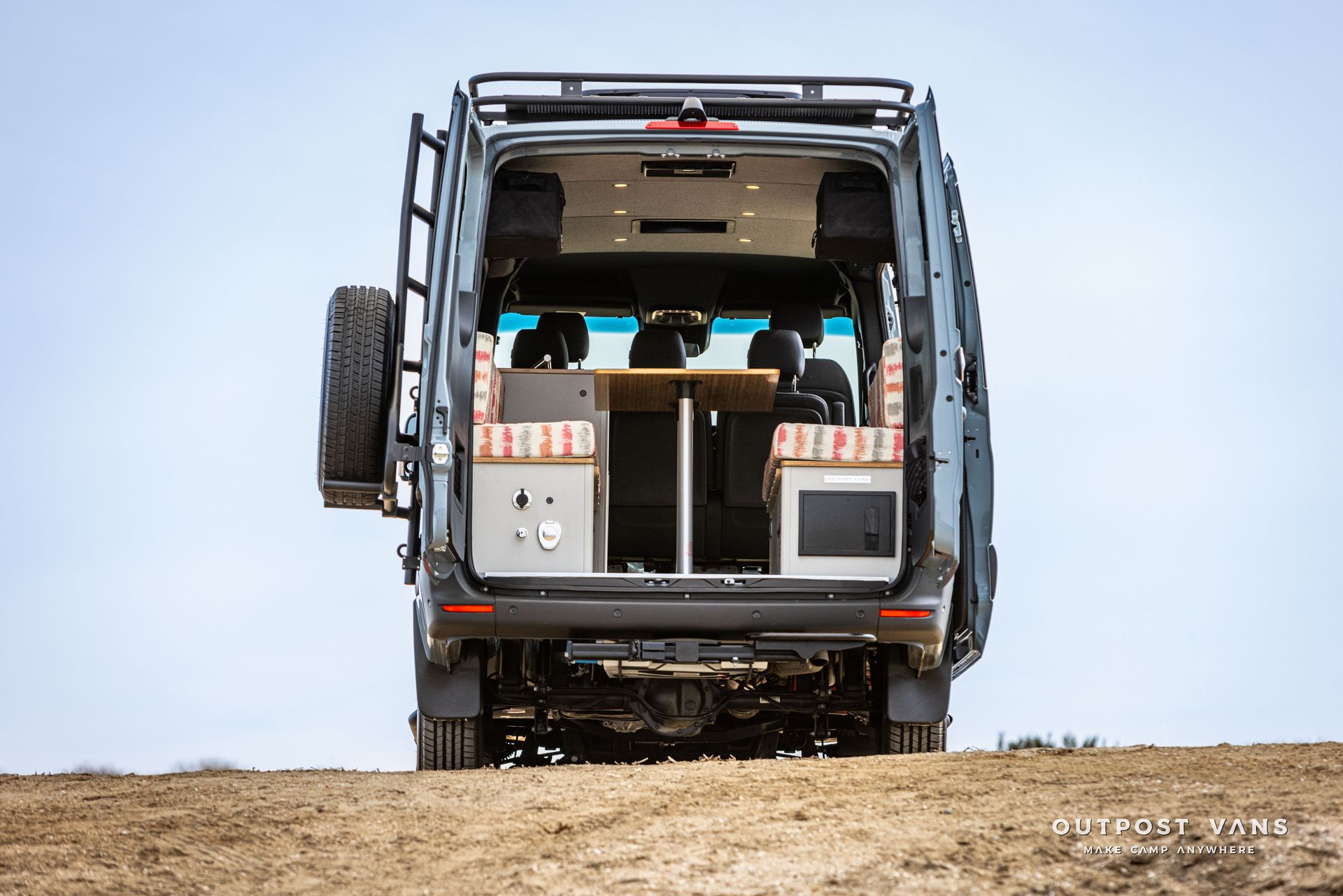 A camper van is parked on top of a dirt hill.
