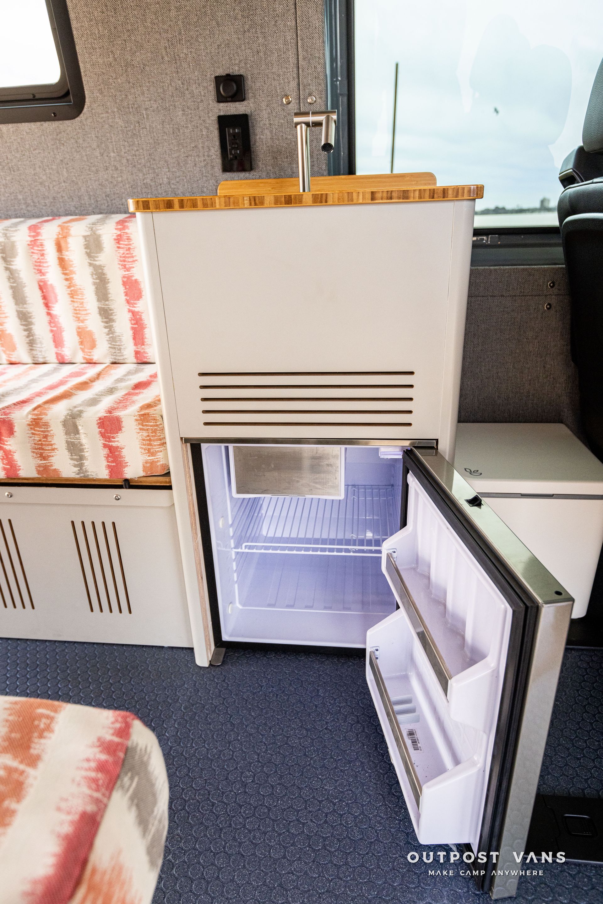 A small refrigerator is open in a camper van.