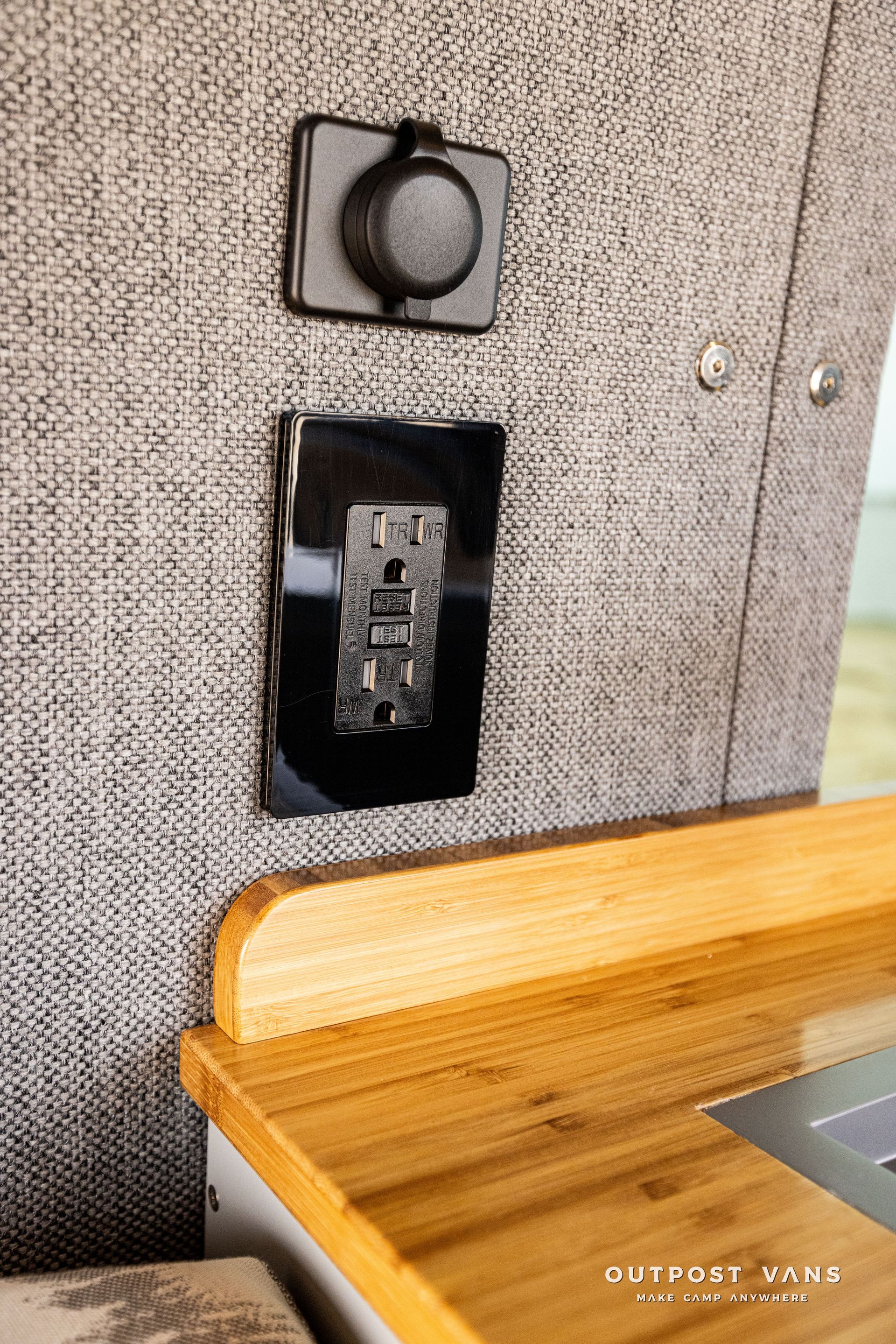 A close up of a electrical outlet on a wall next to a wooden counter.
