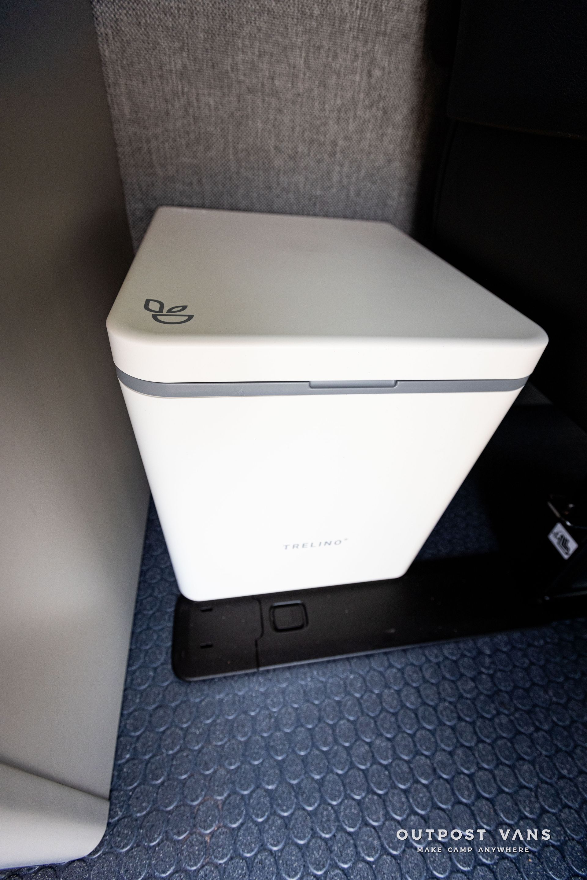 A white box is sitting on a blue floor next to a wall.