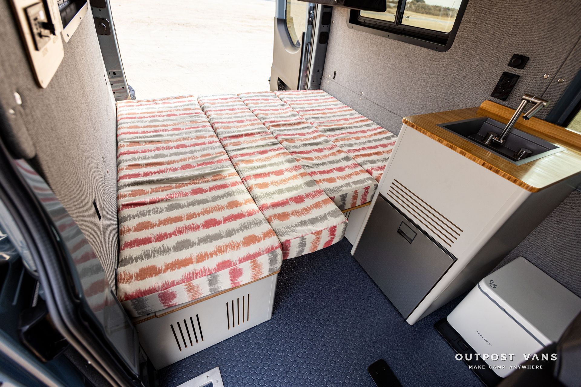 The inside of a van with a bed and a sink.