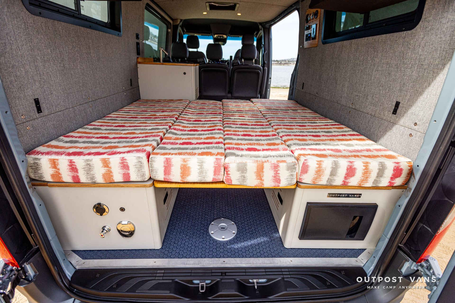 The back of a van with a bed in it.