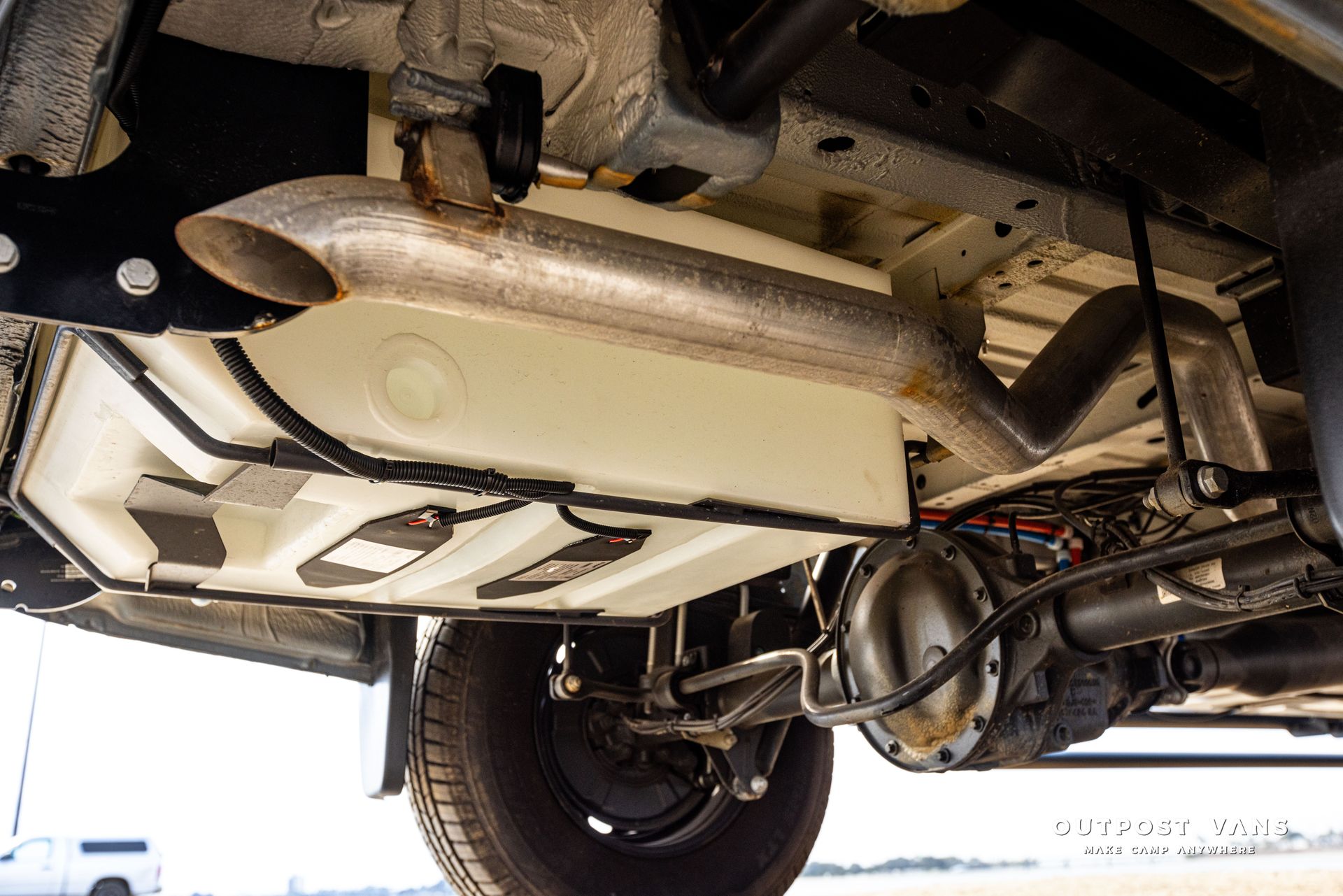 The underside of a truck with a fuel tank and exhaust pipe.