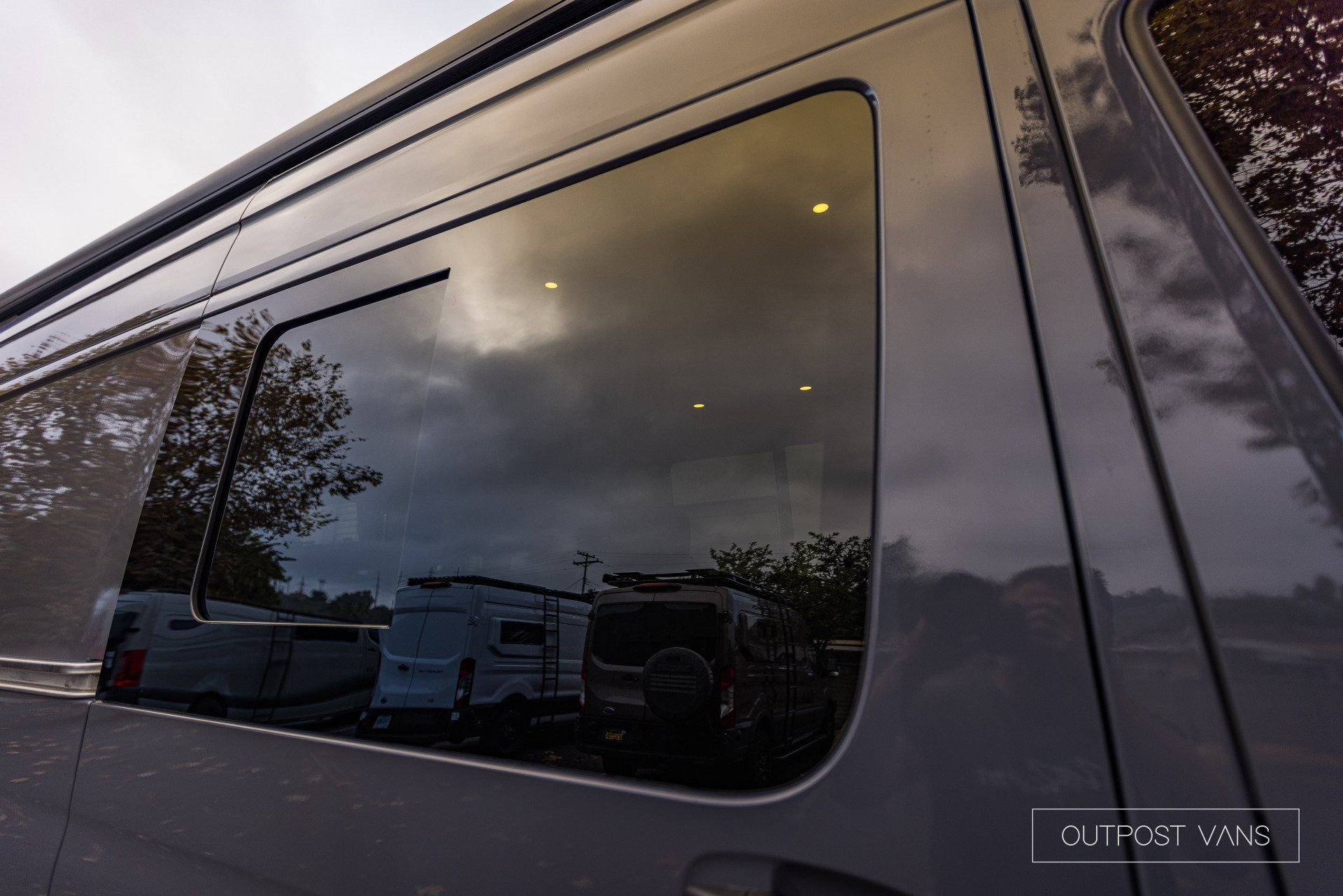 a close up of a van window with a cloudy sky reflected in it .