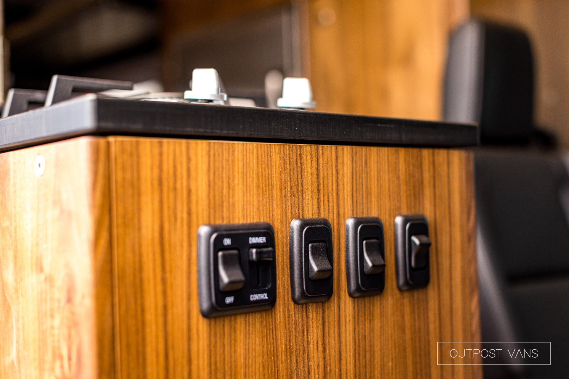 A wooden cabinet with a stove top oven and a bunch of switches on it