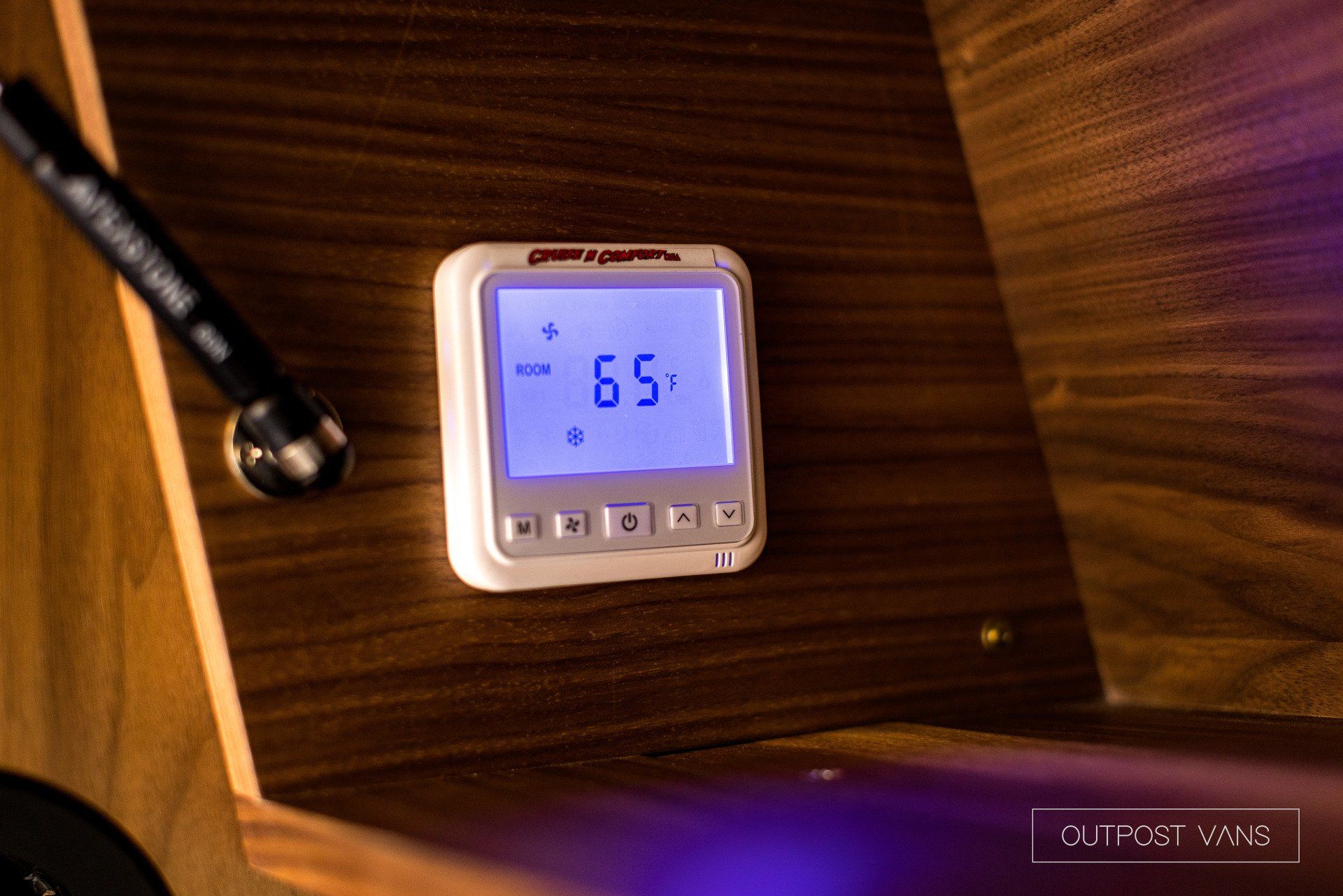 A digital thermostat is sitting on a wooden table.