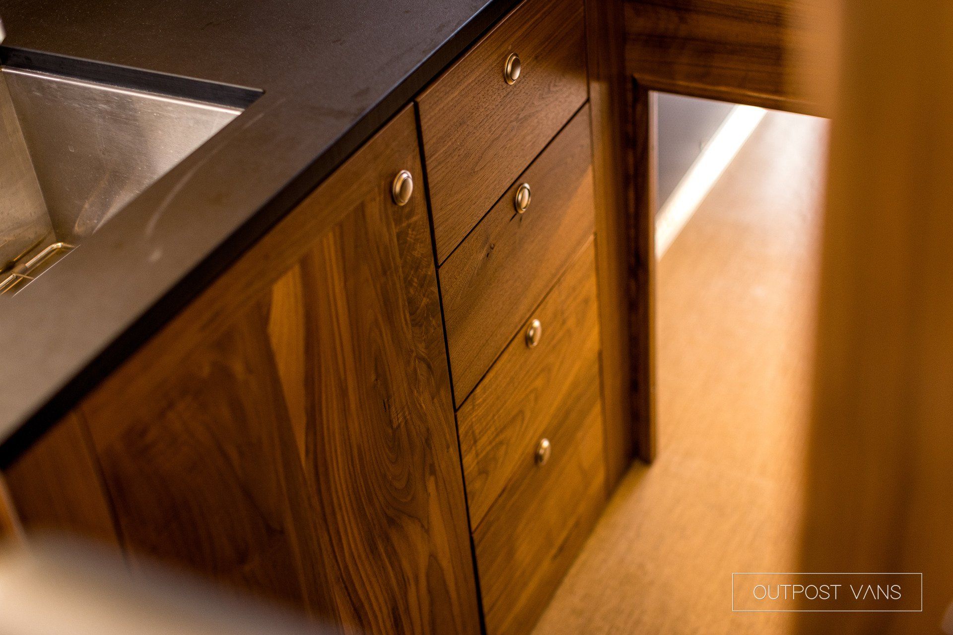A kitchen with wooden cabinets and drawers and a sink