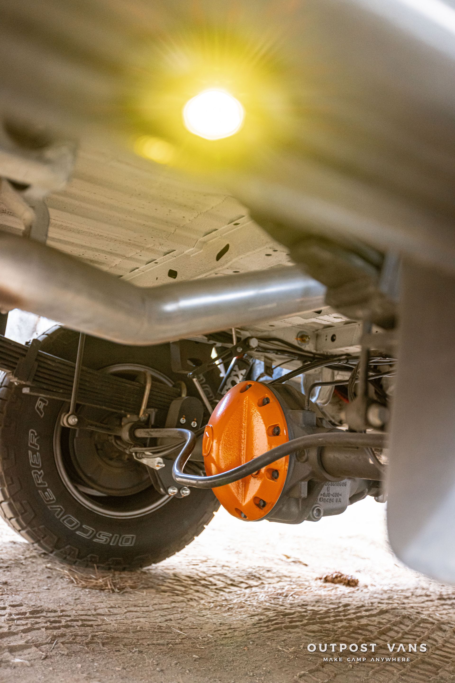 A close up of the underside of a car with a yellow light.