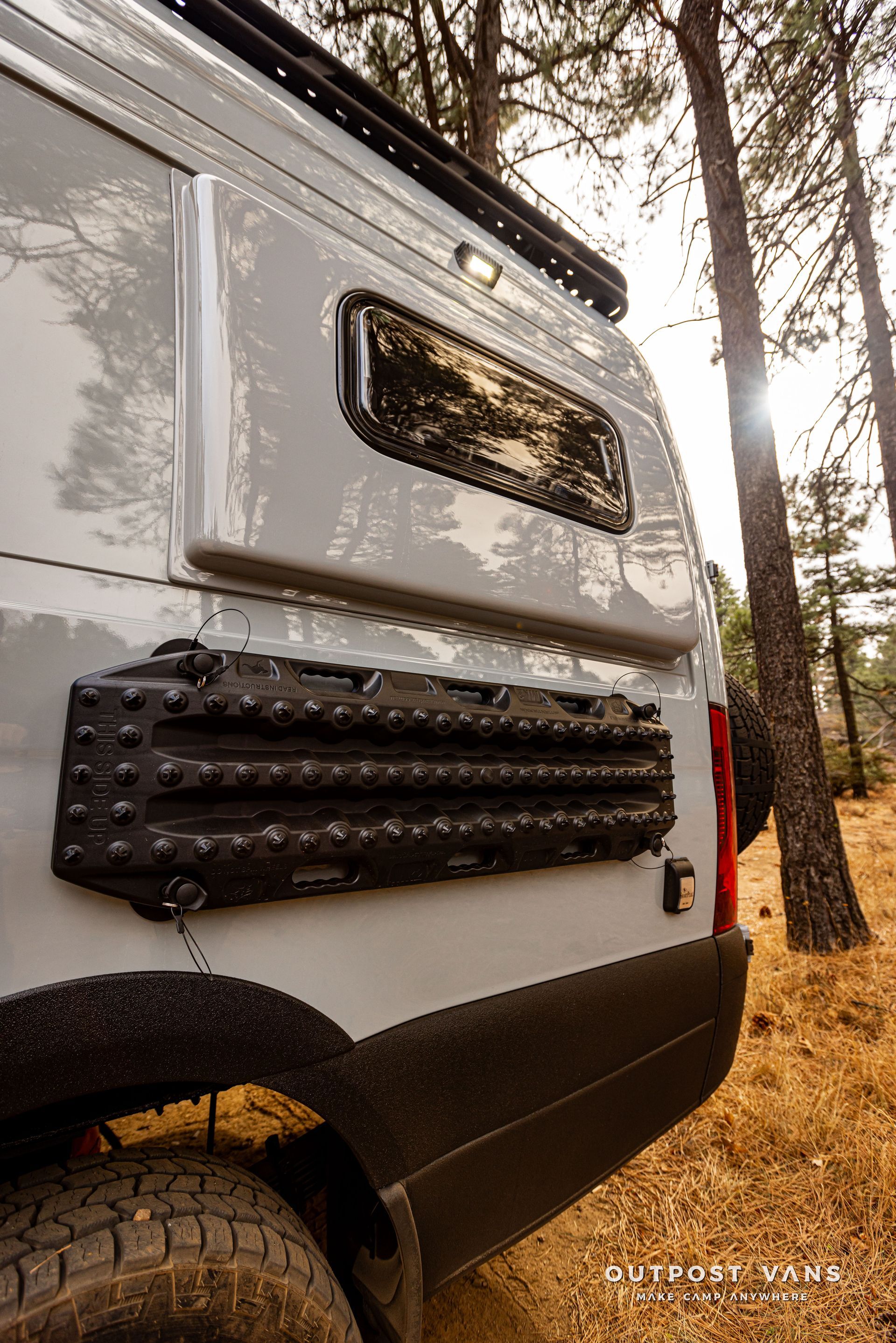 A white van is parked in the middle of a forest.
