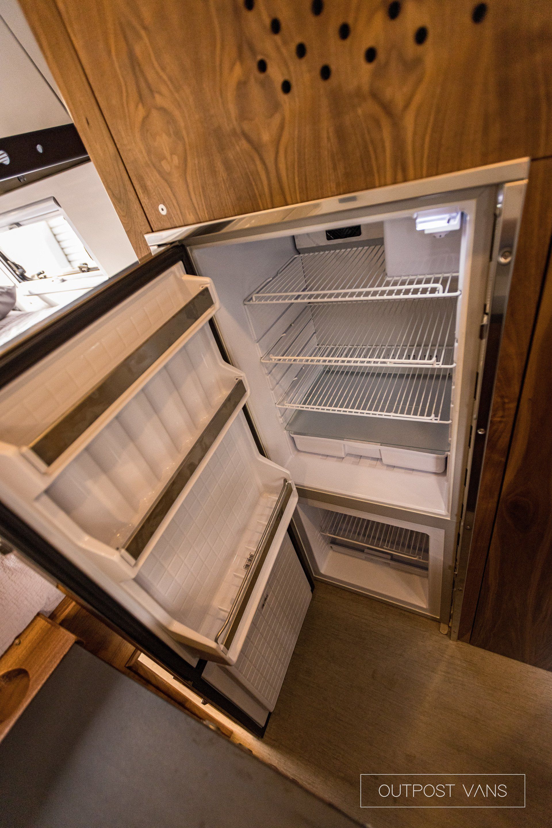 An empty refrigerator with the door open in a kitchen.