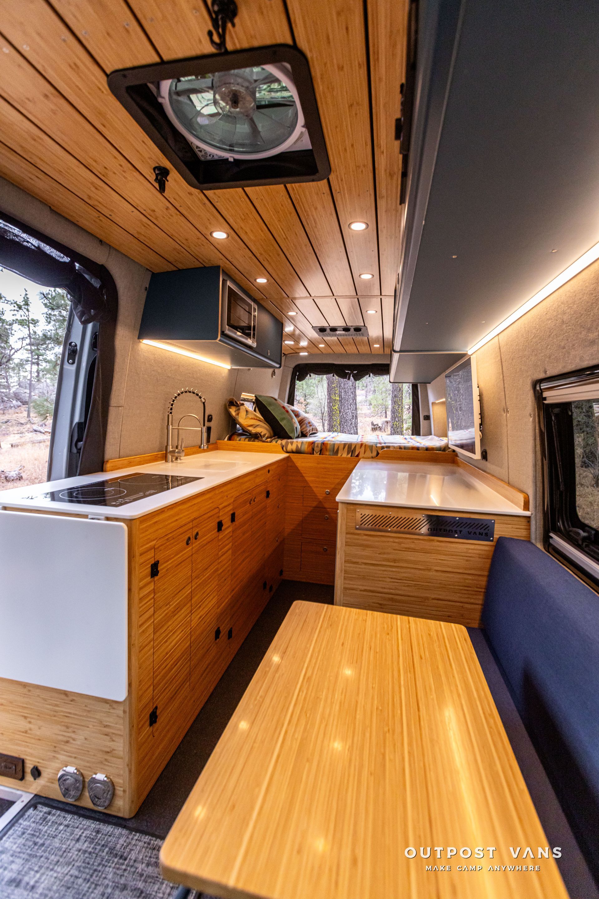 A kitchen in a van with wooden cabinets and a table.