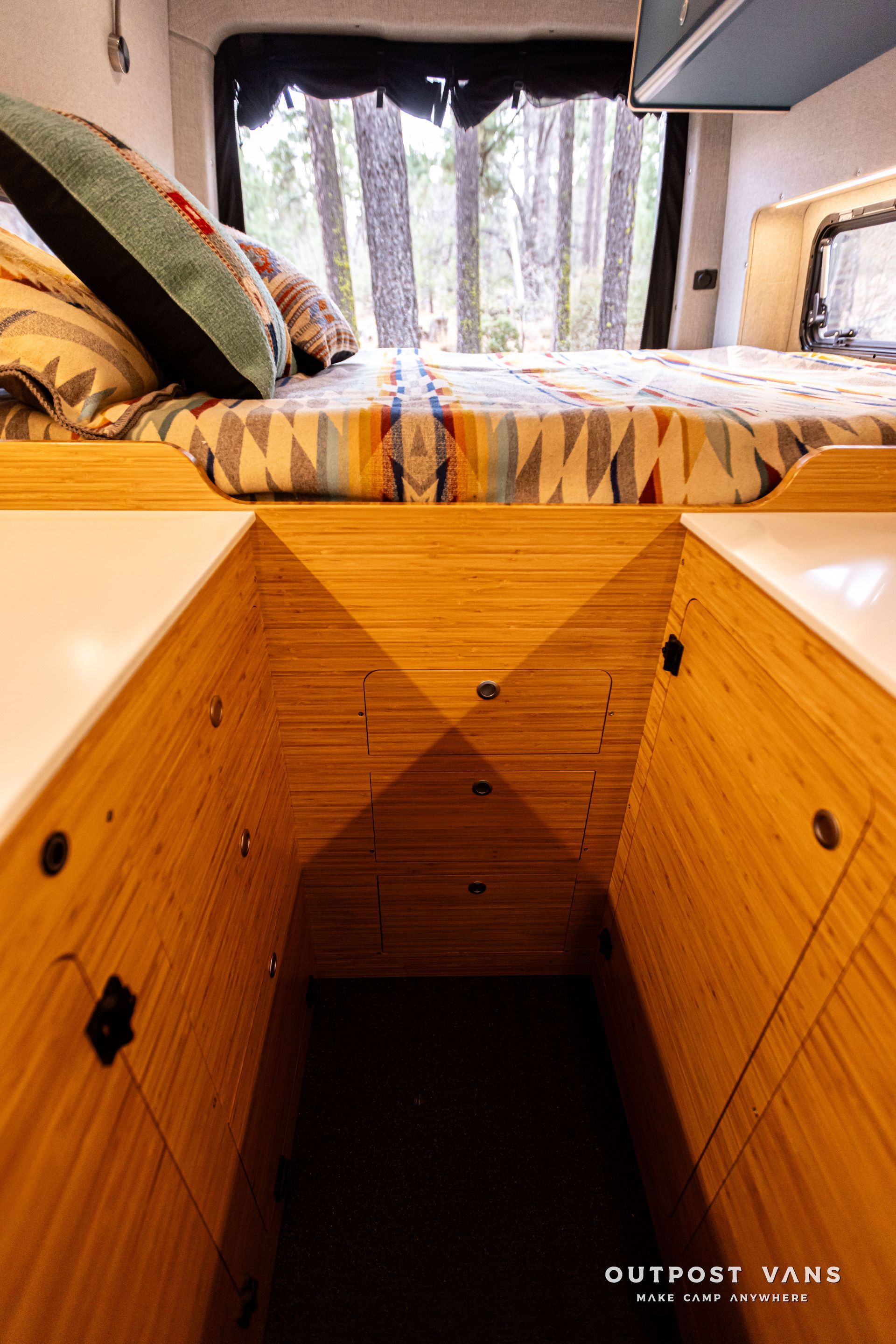 A bed is sitting on top of a wooden platform in a camper van.