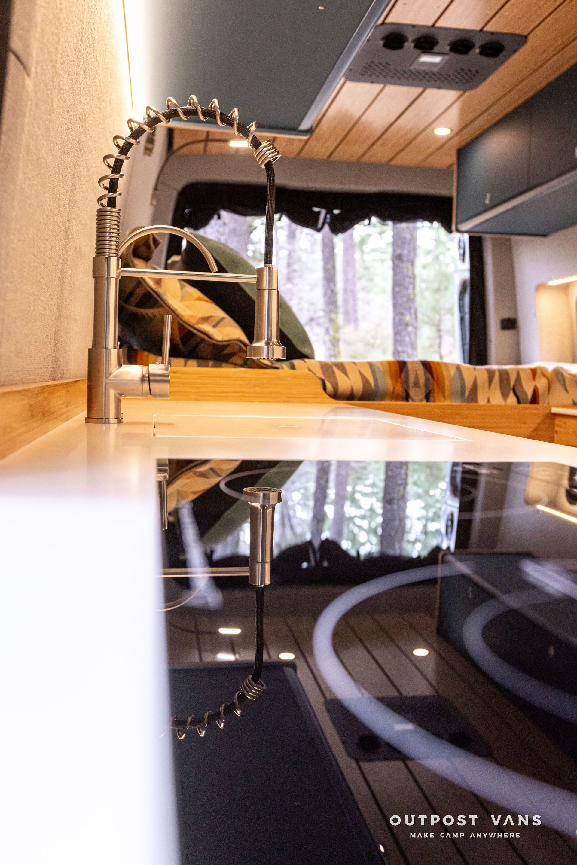A kitchen in a van with a sink and a stove top oven