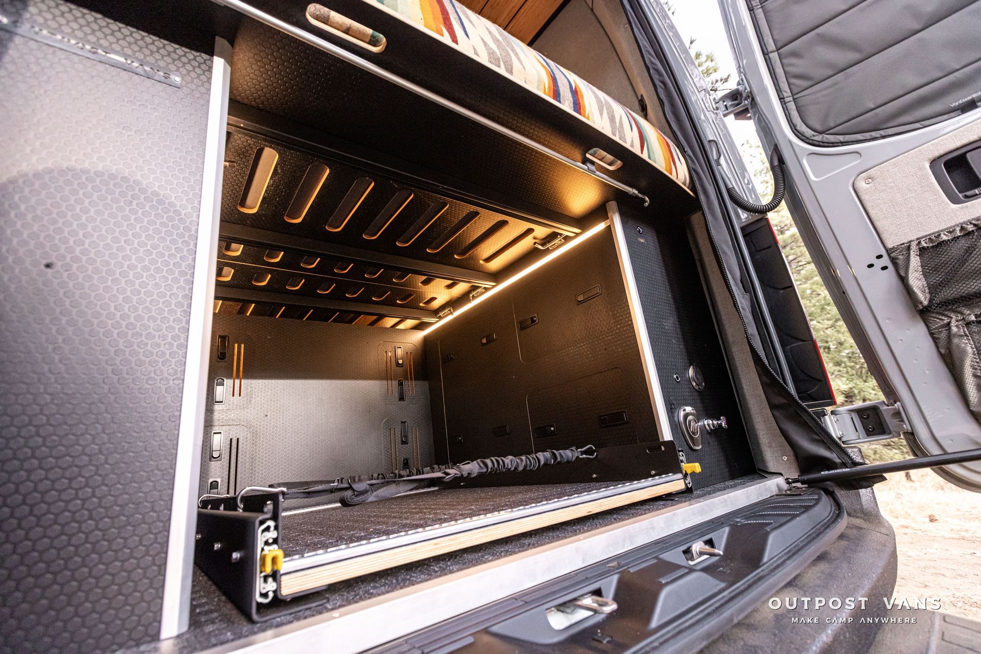 The back of a van with the door open and a shelf in the back.