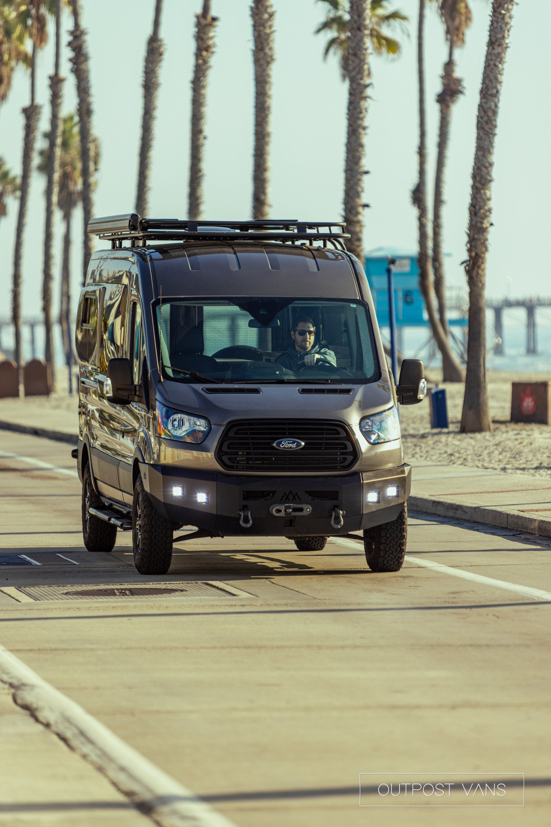 a van is driving down a street next to a beach .