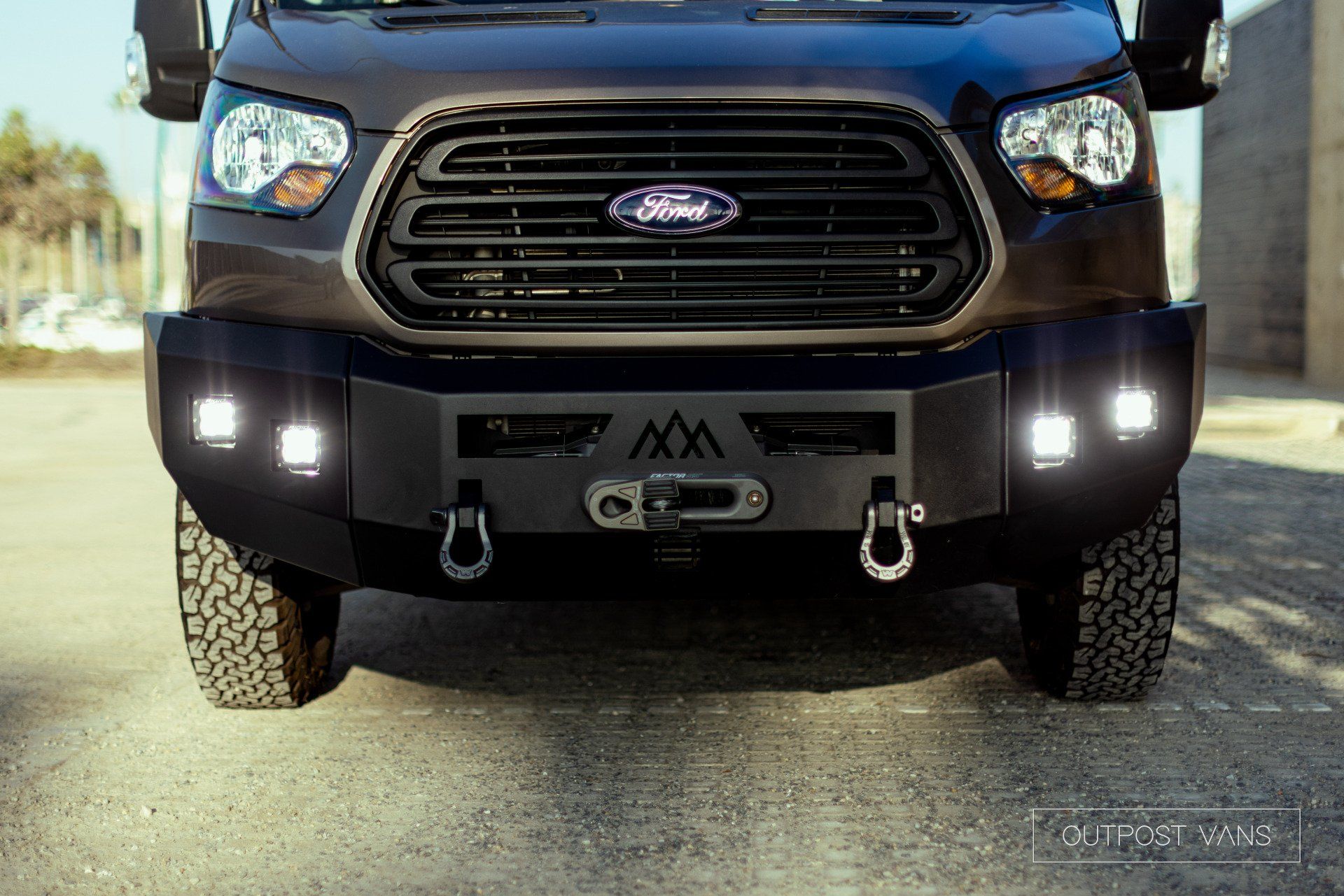 the front end of a ford transit van with a bumper and lights .