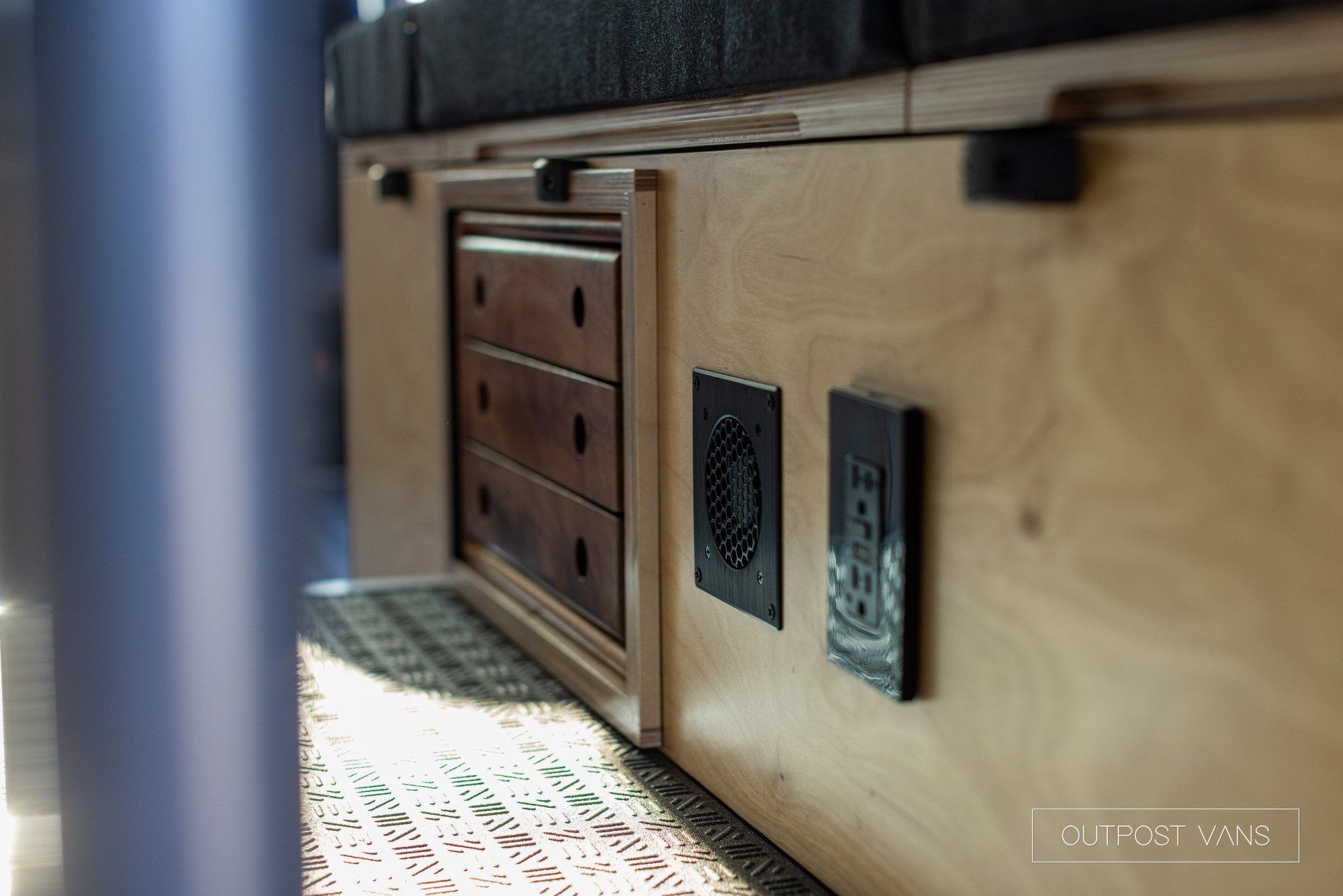 a wooden cabinet with drawers and electrical outlets on the side of it .