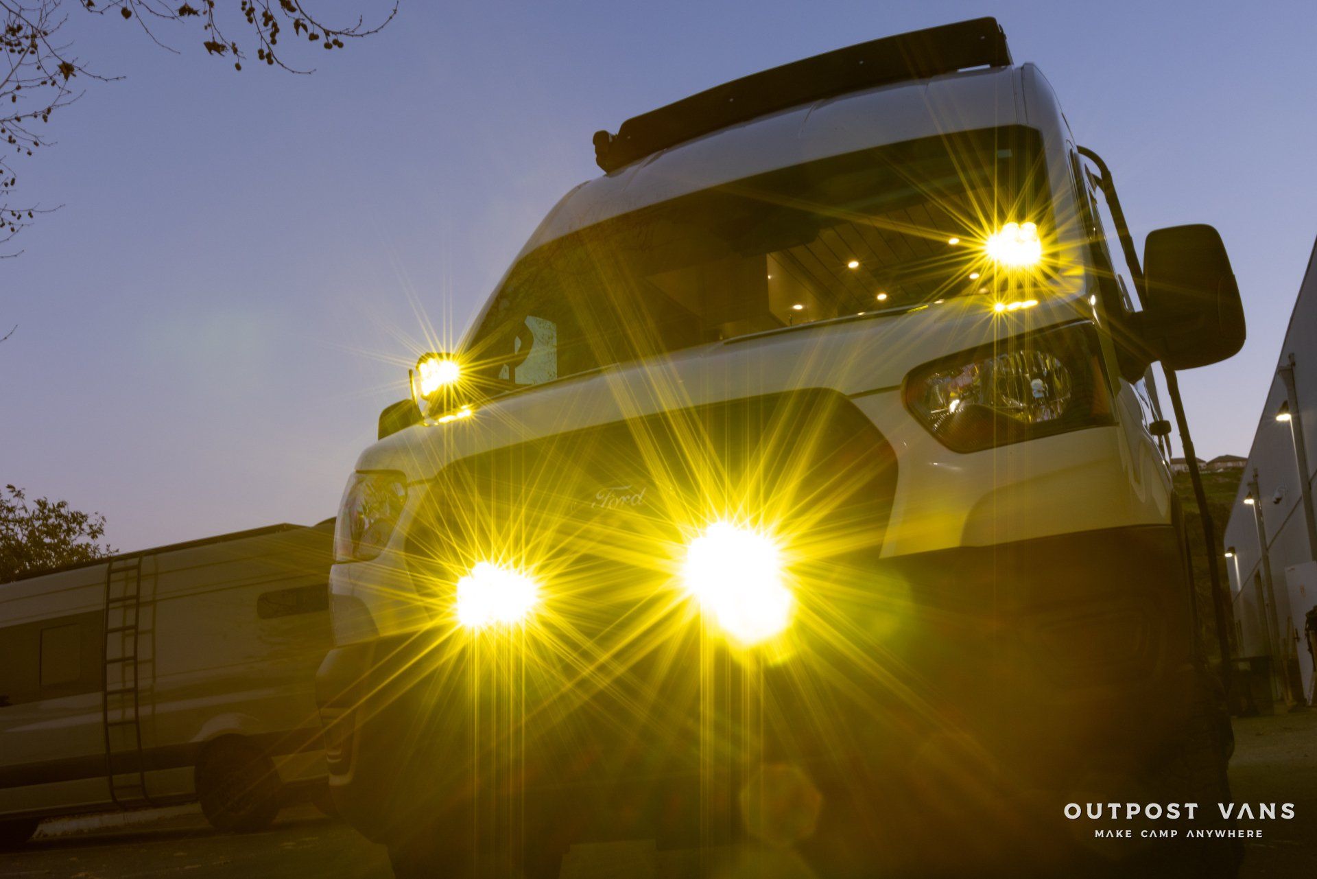 a white van with yellow lights is parked in a parking lot .