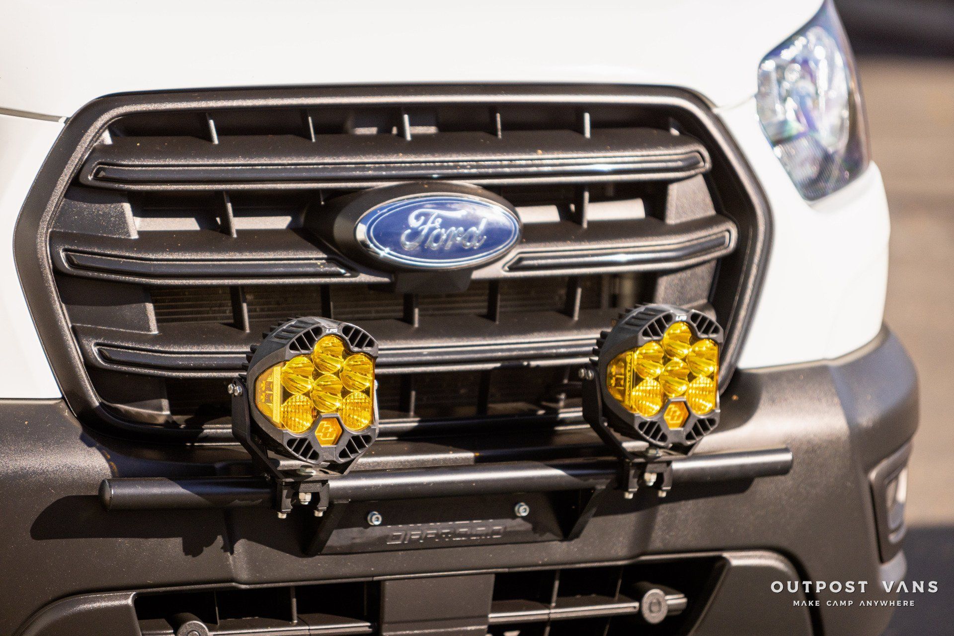the front of a white ford van with yellow lights on it .