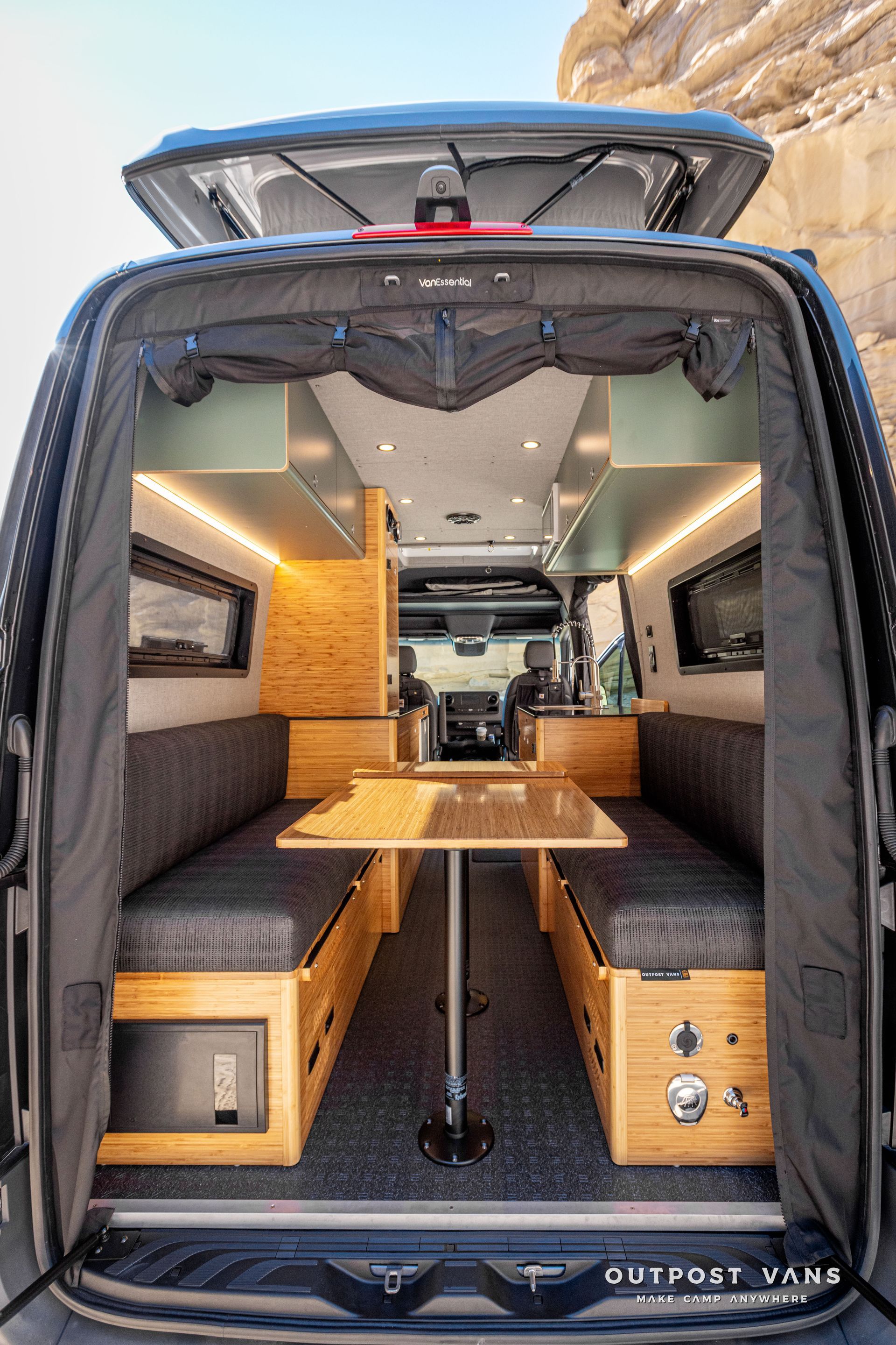 The inside of a camper van with a table and benches that convert to a bed