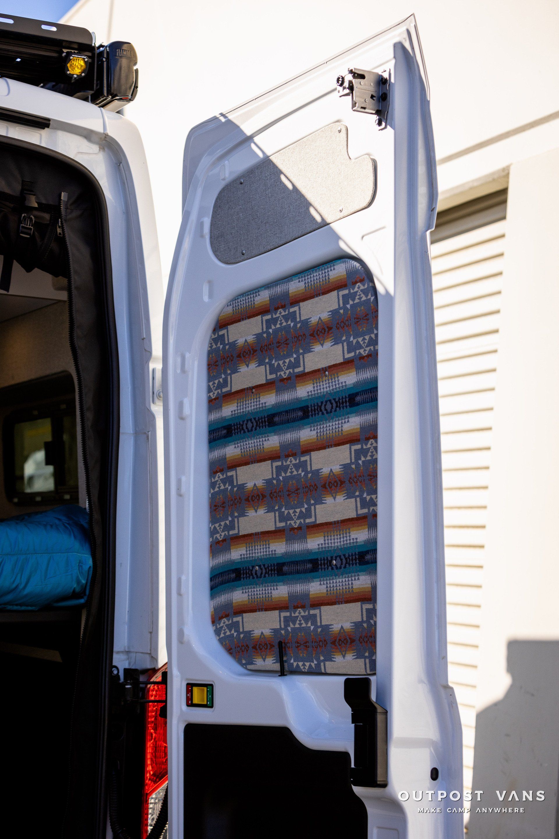 a white van with the door open is parked in front of a building .