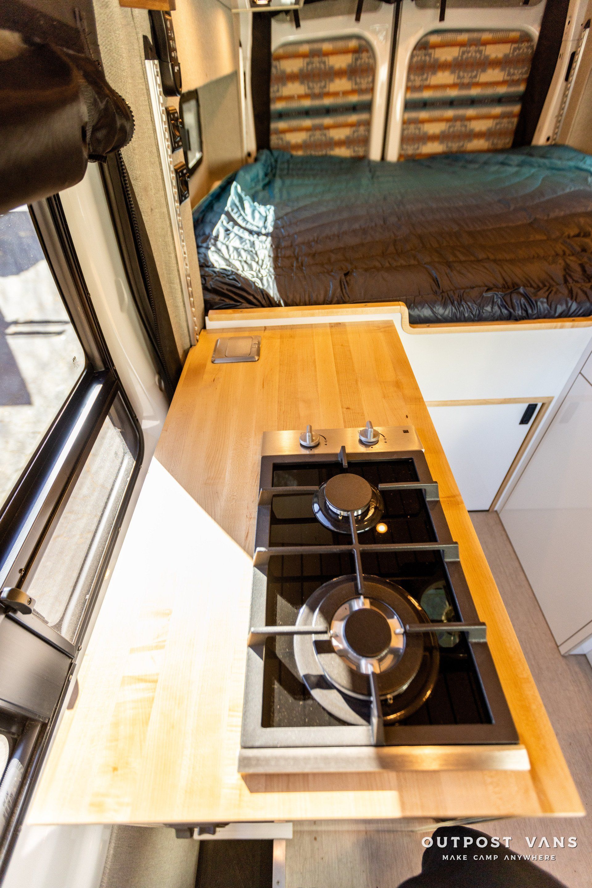 a stove top oven is sitting on top of a wooden counter in a camper van .