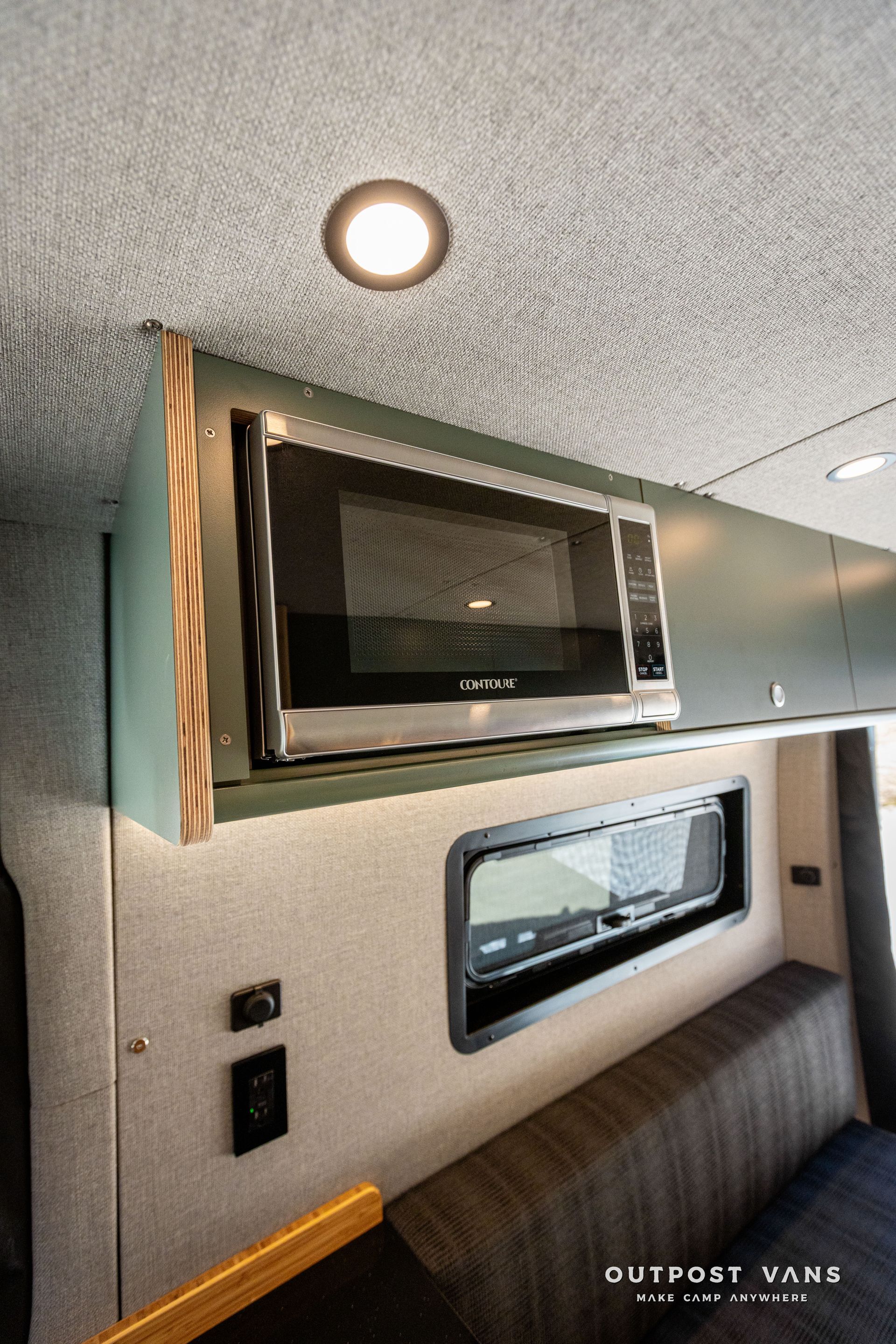 A microwave oven is sitting on top of a shelf in a van.