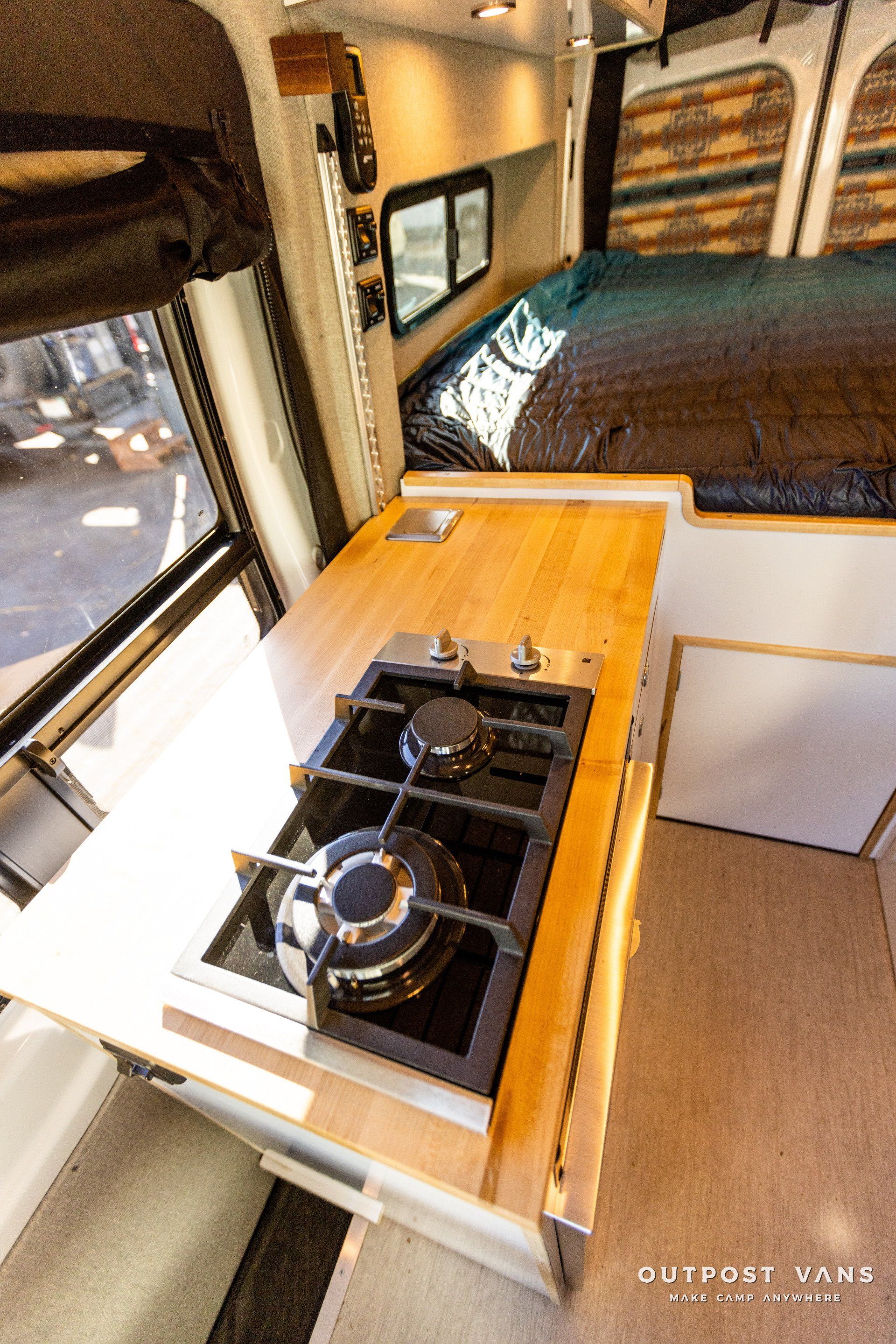 a camper van with a gas stove and a wooden counter top .