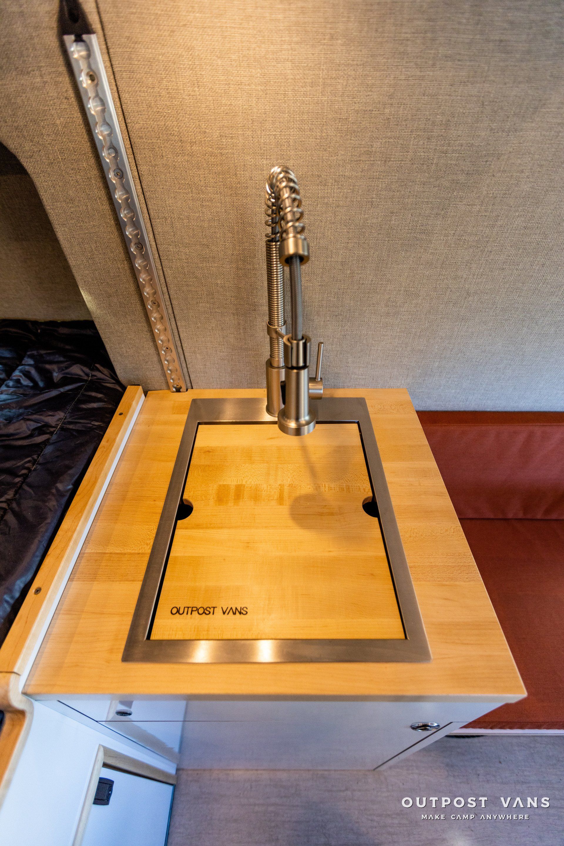 a stainless steel sink with a wooden counter top in a camper van .
