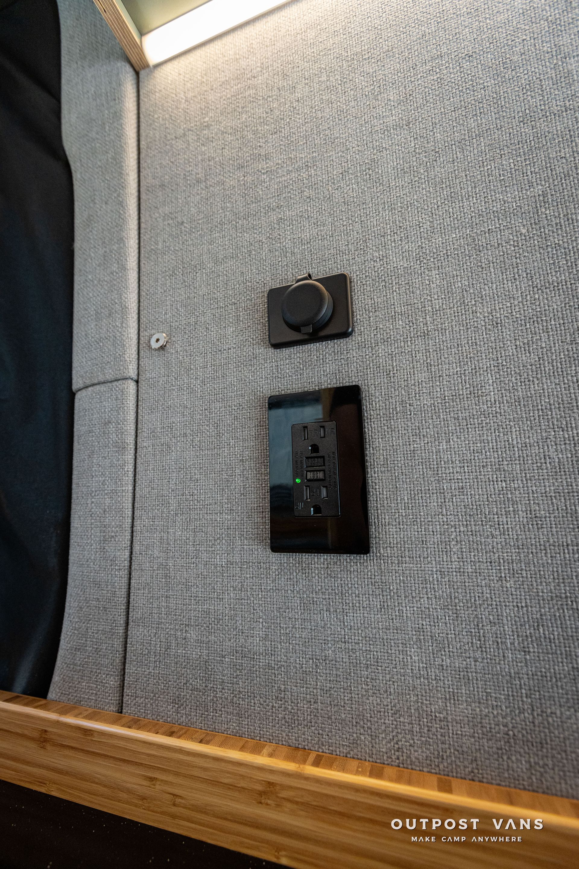 A close up of a light switch on a wall next to a bed.