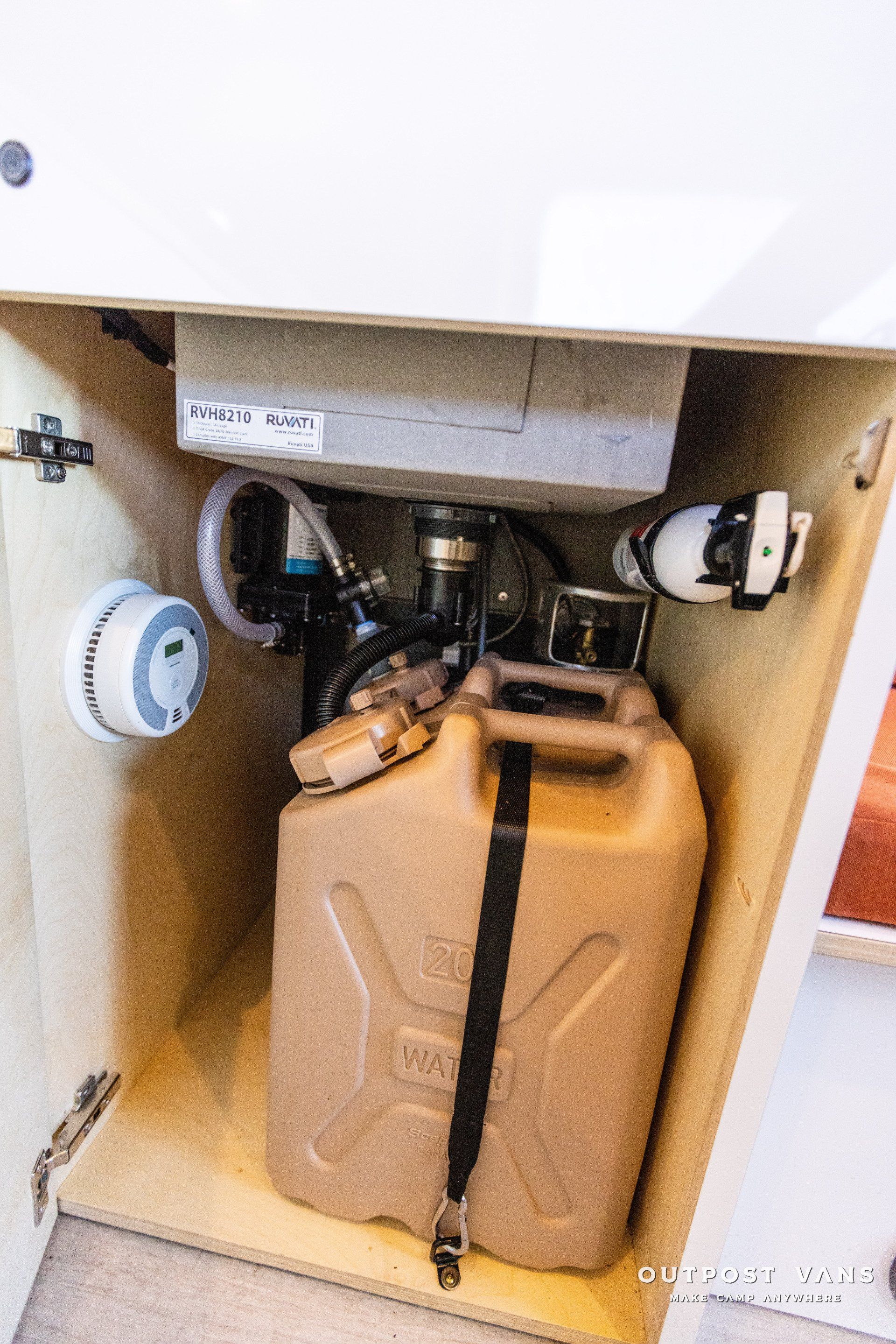 a jerry can is sitting under a sink in a cabinet .