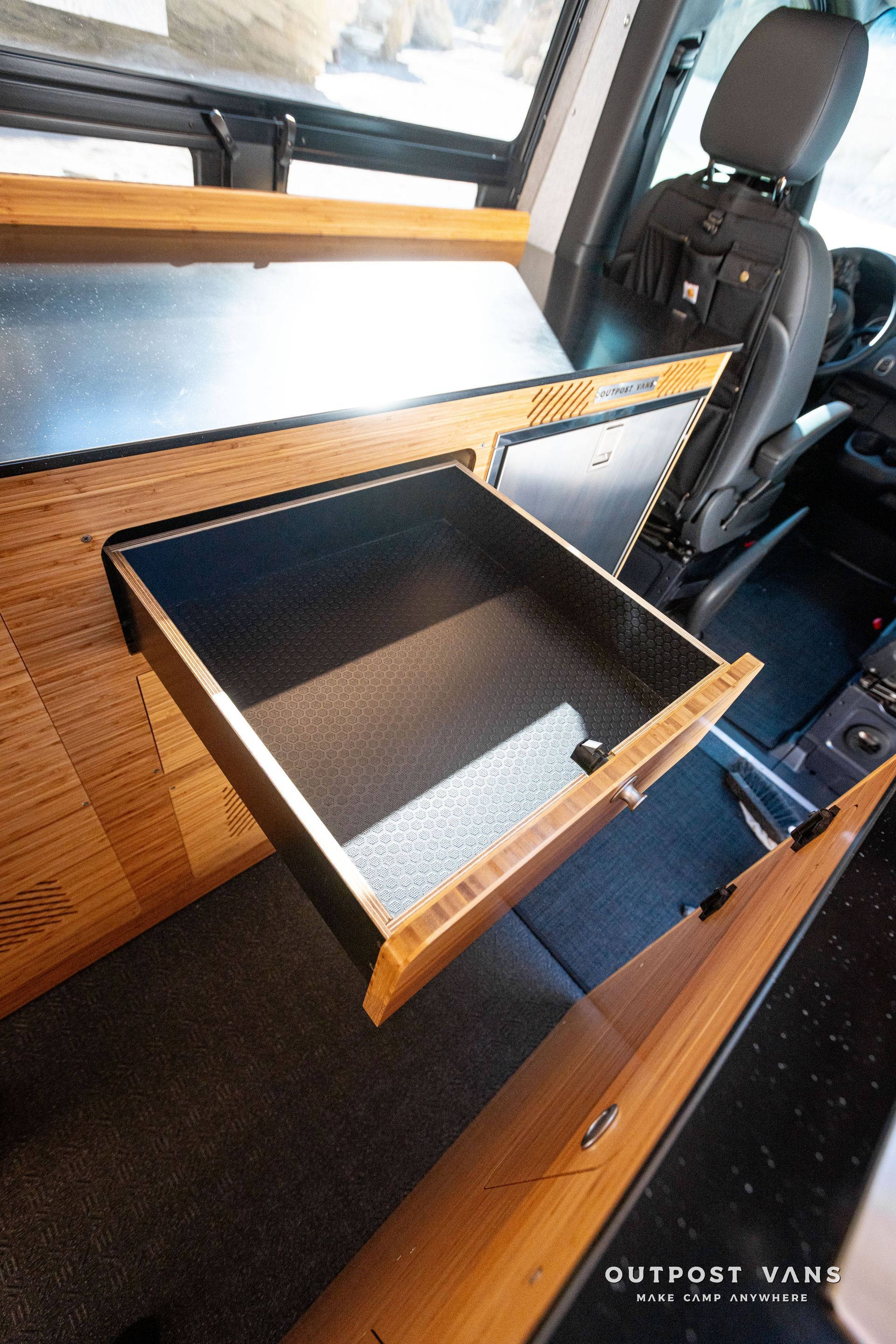 A wooden drawer is open in the back of a van.