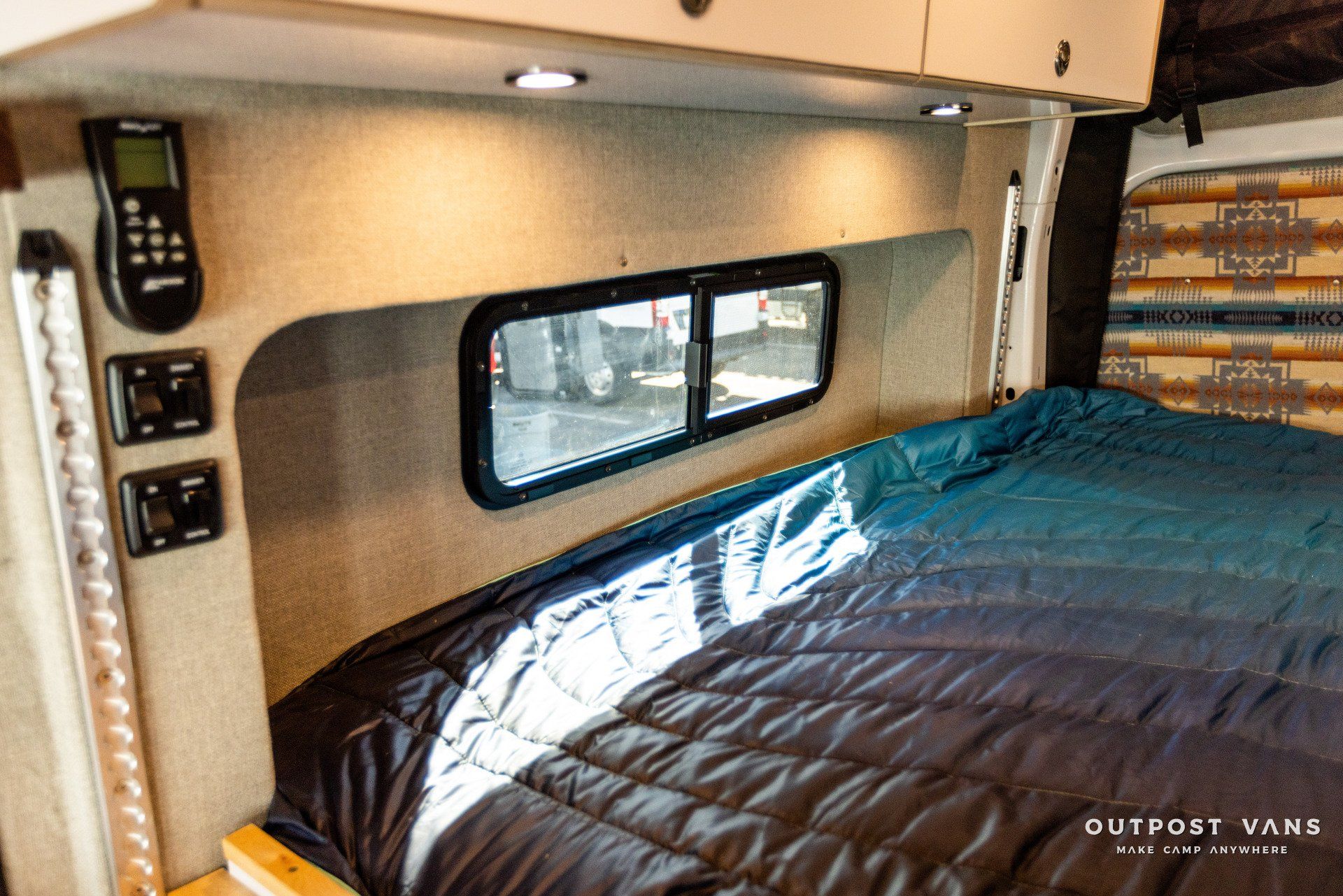 there is a bed in the back of a van with a window .