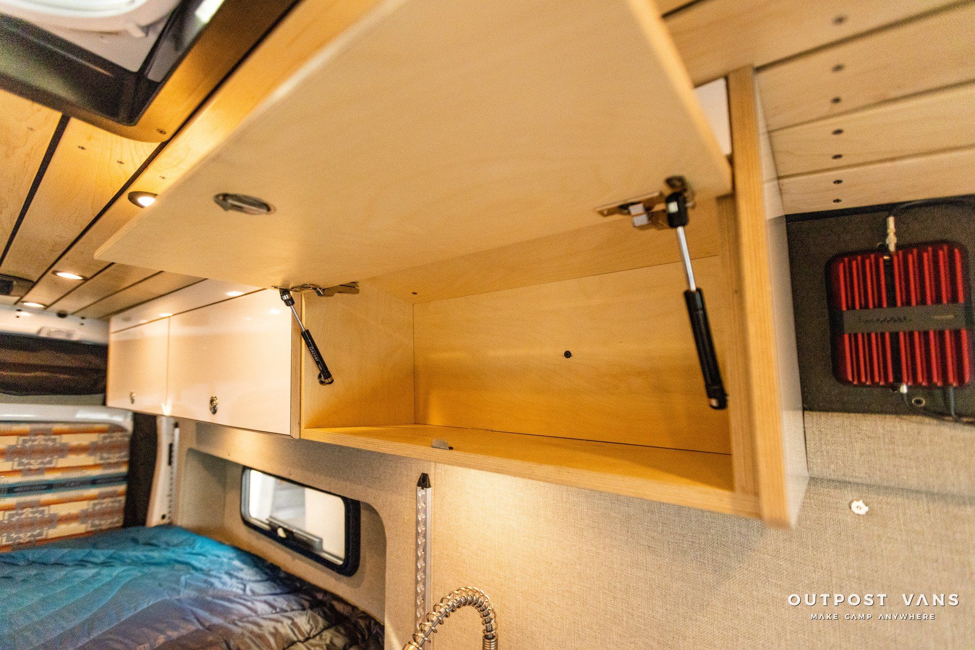a camper van with a bed , sink , and cabinets open .